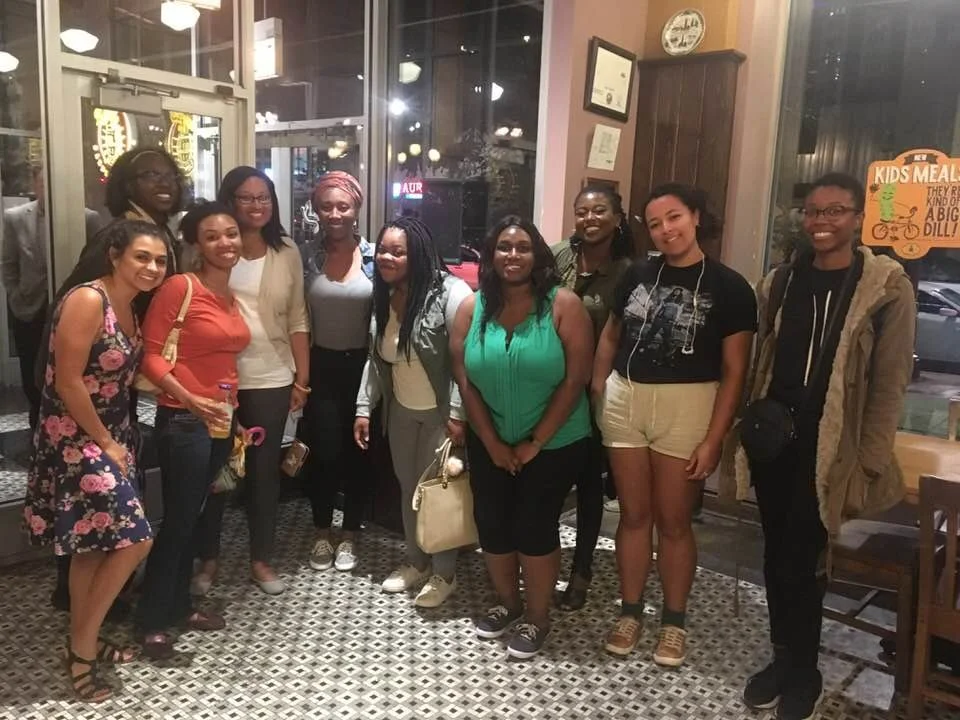 A group of ten people standing together inside a restaurant, smiling for a photo.