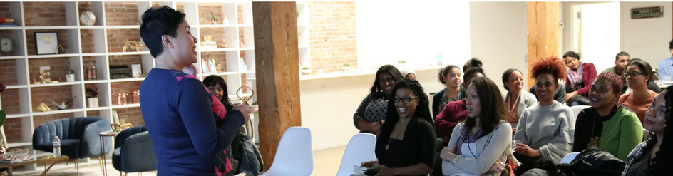Workshop facilitator presenting to a group of filmmakers seated in a community space.