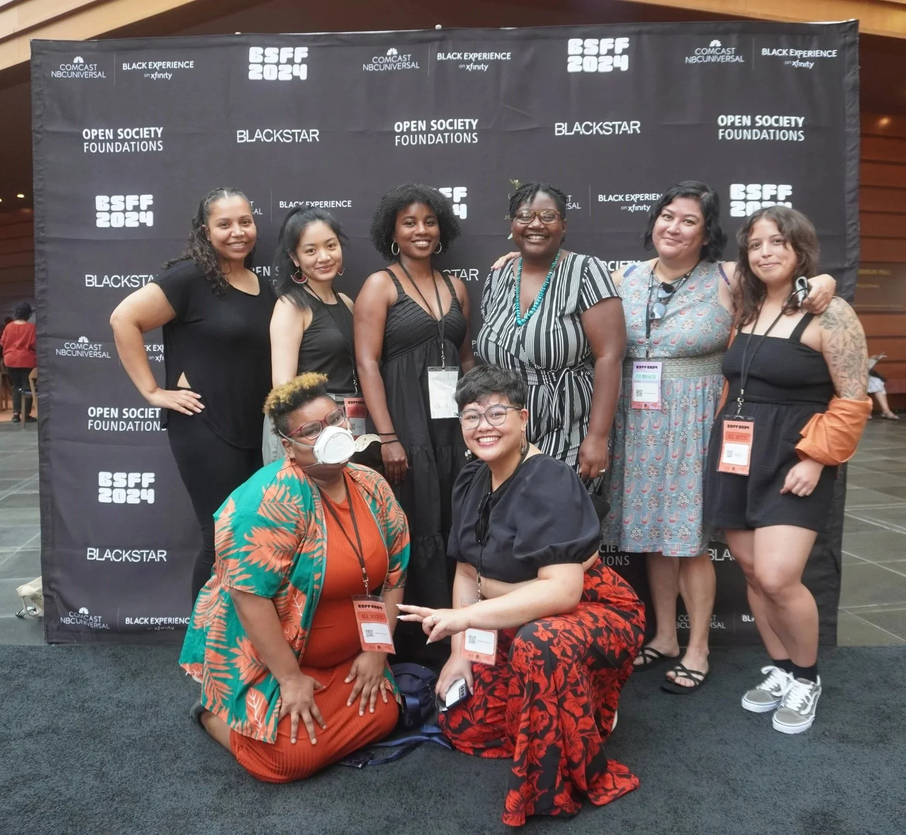Group of people at a conference, standing and sitting in front of a black backdrop with white logos and text including 'BSFF 2024', 'Open Society Foundations', 'Black Experience', and 'Blackstar', smiling and posing for a photo.