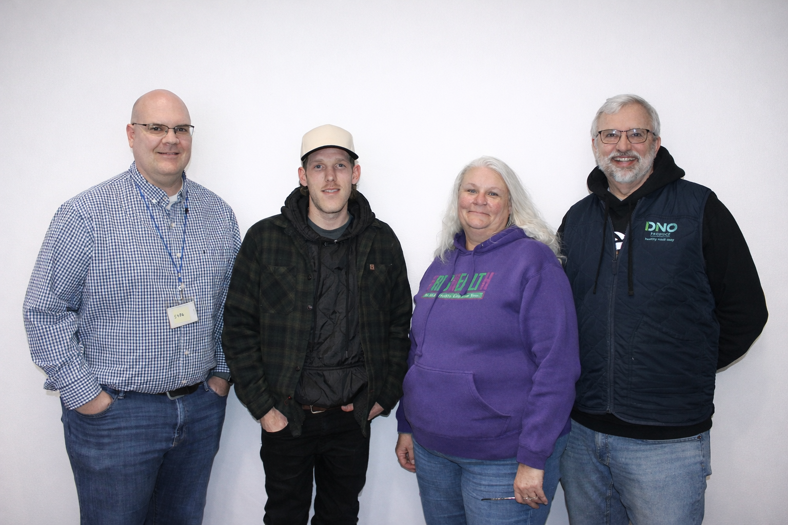 Group of four people standing against a white background, smiling at the camera.