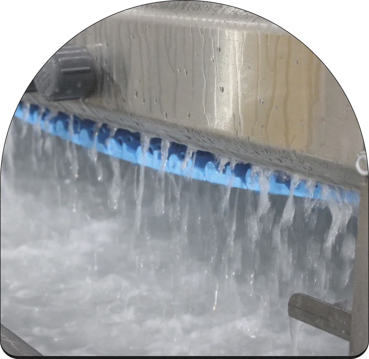 Close-up of a metal surface with water flowing from a blue drainage grate.