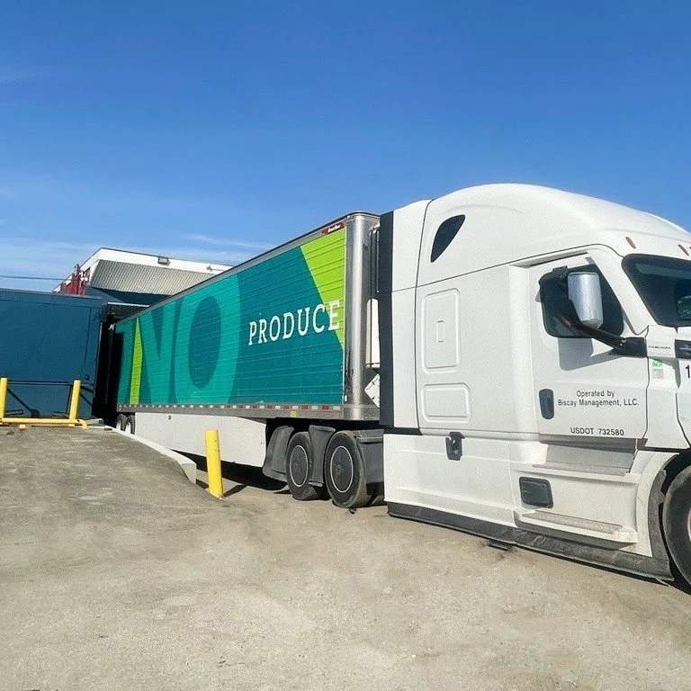 Semi-truck with a colorful trailer parked outside a building under a clear blue sky.