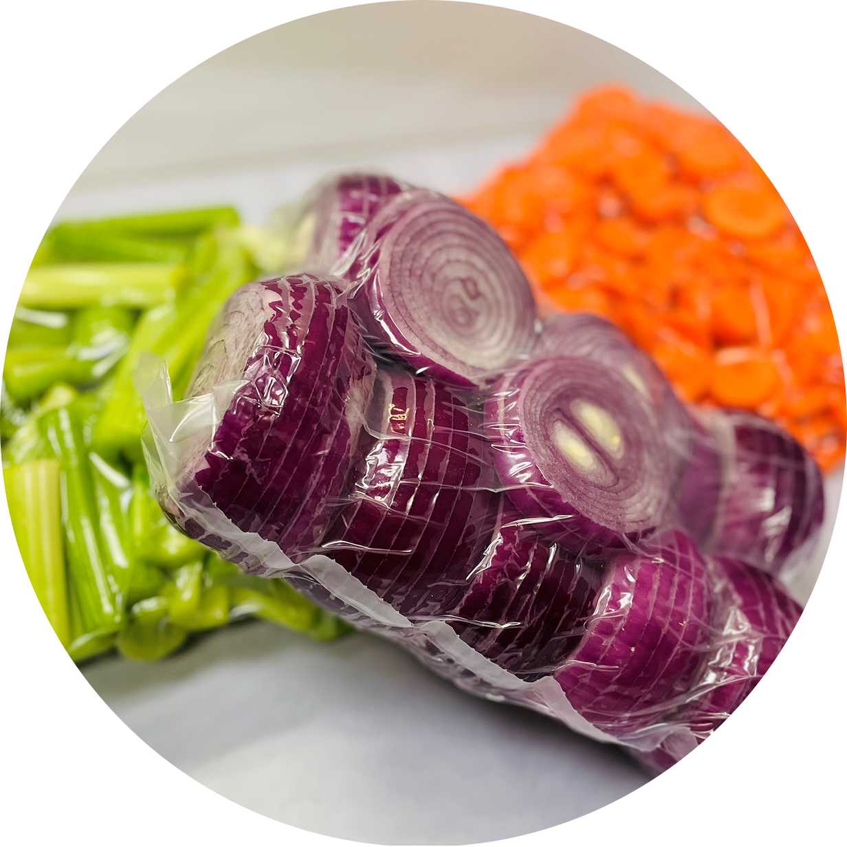 Fresh celery, red onions, and shredded carrots on a white surface.