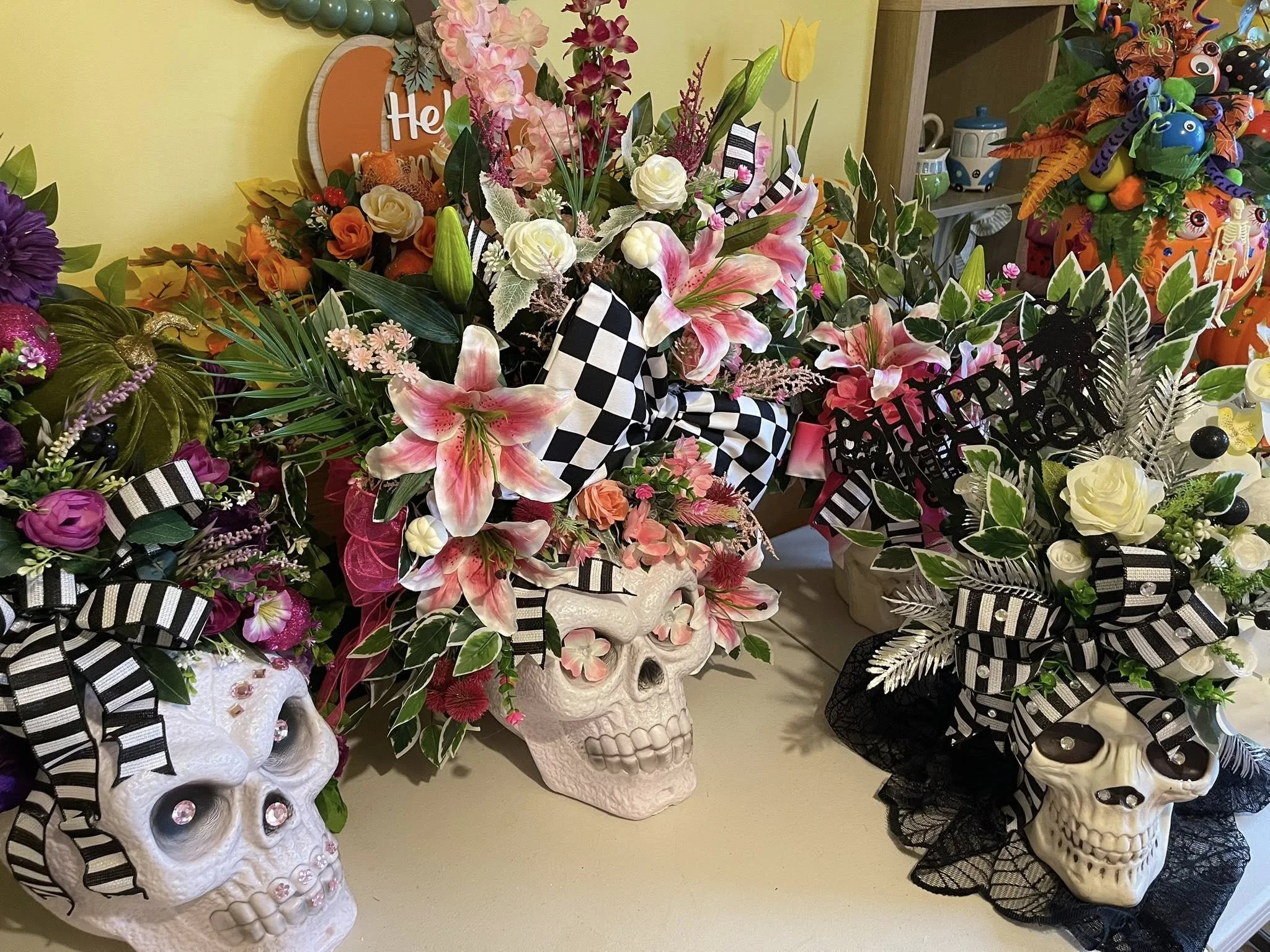 Skull-shaped vases with flowers and decorative ribbons, celebrating Halloween and possibly a birthday.
