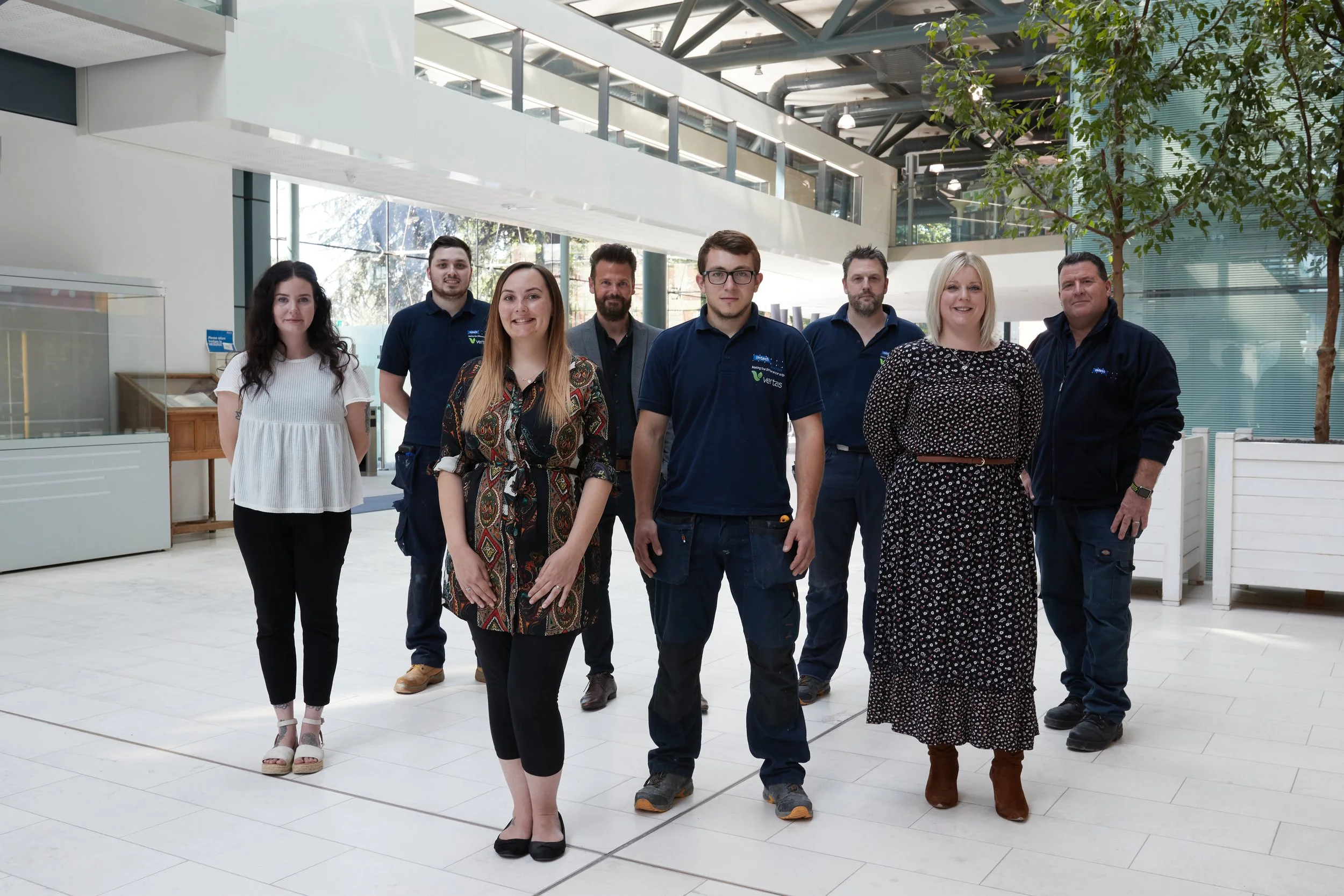 Group of nine people standing indoors, posing for a photo.