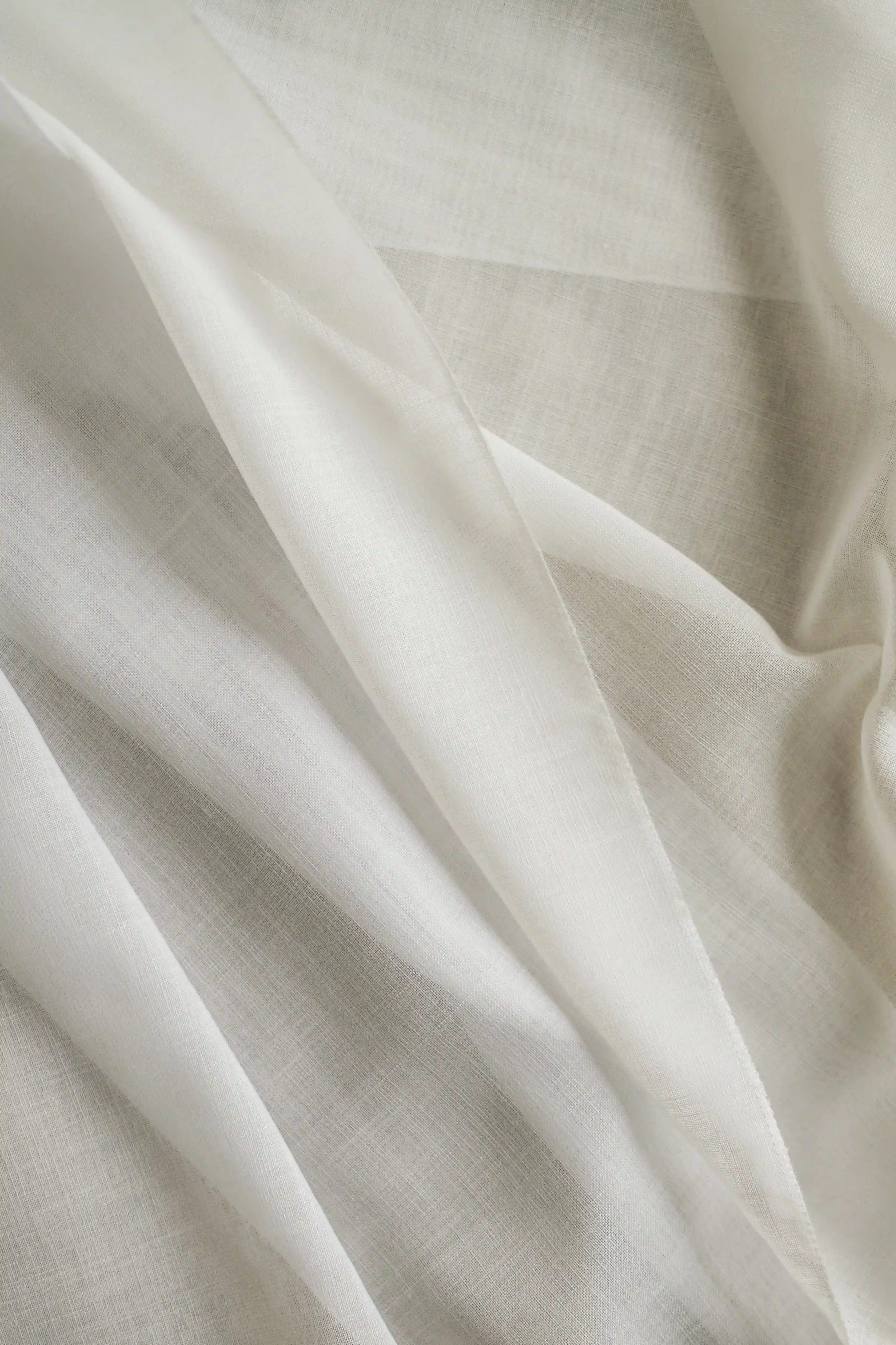 Close-up of cream-colored fabric with a smooth, textured surface and folds.