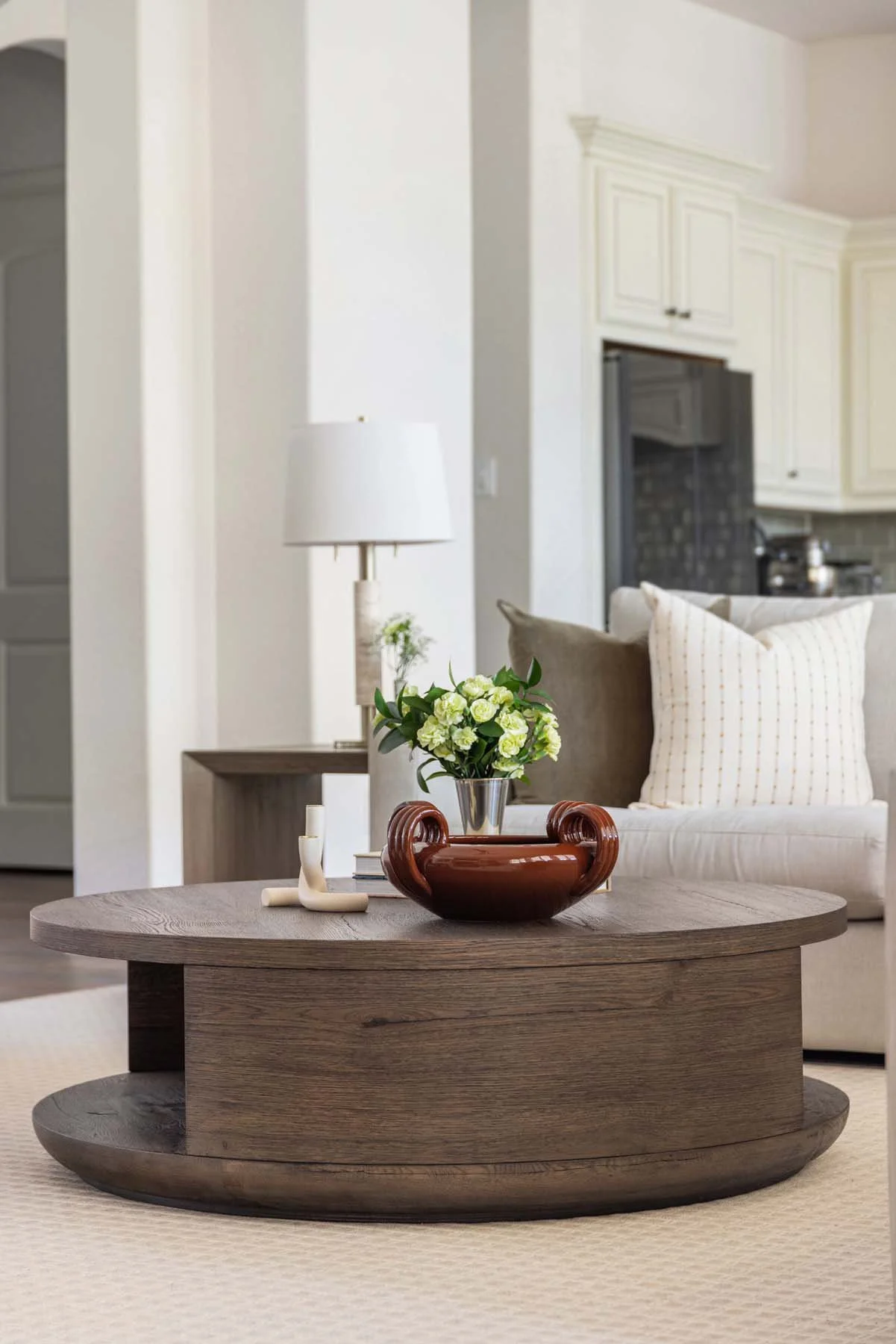 Living room with a wooden coffee table, white sofa with pillows, lamps, and decorative items.