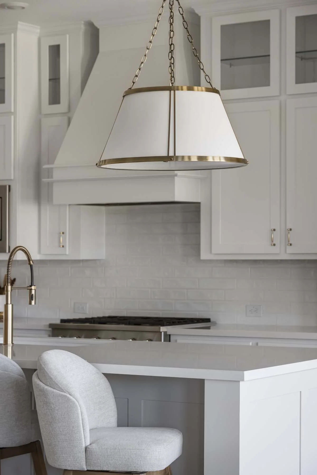 Modern white kitchen with pendant light, white cabinets, and a white brick backsplash.
