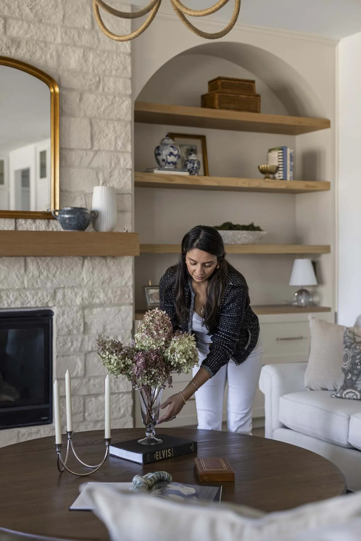 Woman arranging a bouquet of hydrangeas on a living room table.