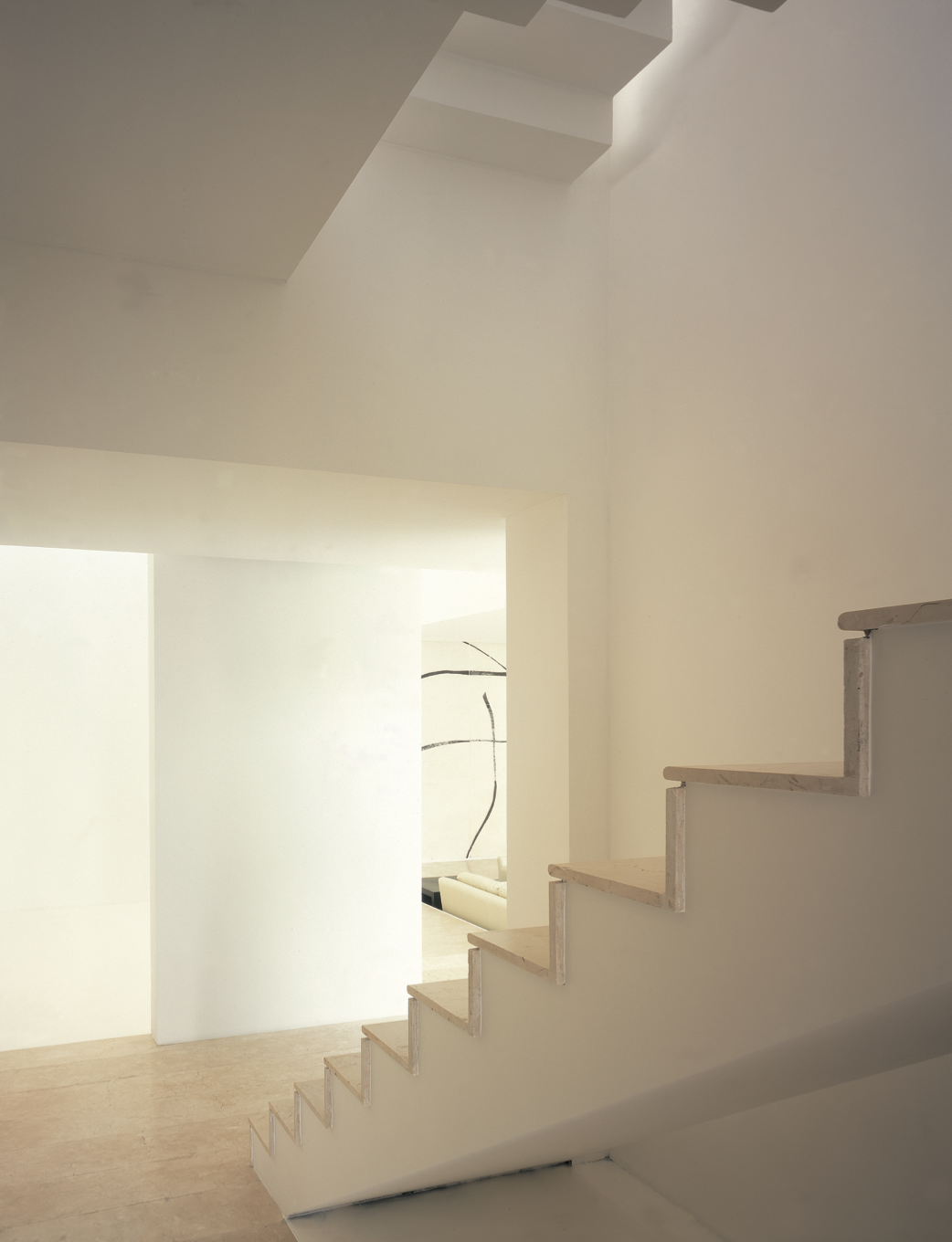 Escalera interior de color blanco con peldaños de madera, en un espacio moderno y minimalista con paredes blancas y suelo de piedra beige. Eucaliptos 65, Architecture & Design by Rafael Aragonés Caballero & Miguel Ángel Aragonés | Taller Aragonés. Ph