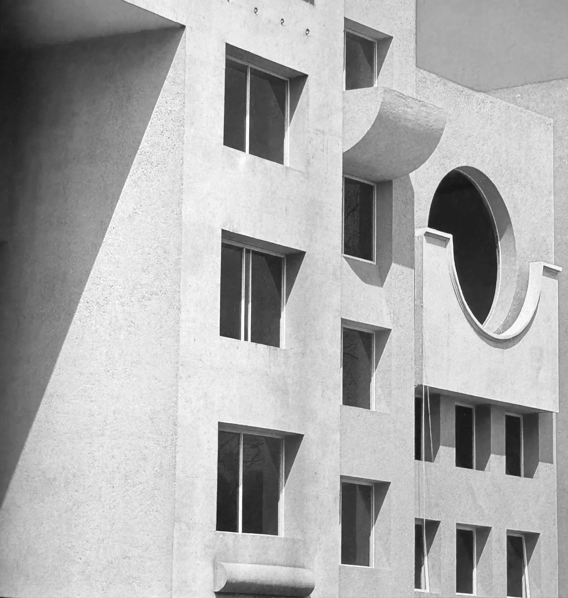 Imagen en blanco y negro de un edificio con ventanas rectangulares y un arco en la parte inferior derecha.