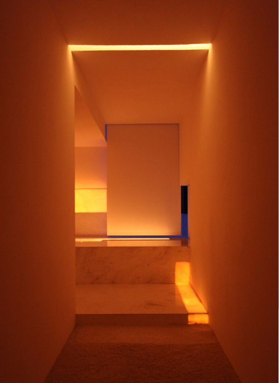 Pasillo con paredes y techo iluminados por luces cálidas y filtradas que crean un ambiente acogedor y moderno. Architecture & Design by Miguel Ángel Aragonés | Taller Aragonés. Photography by Joe Fletcher