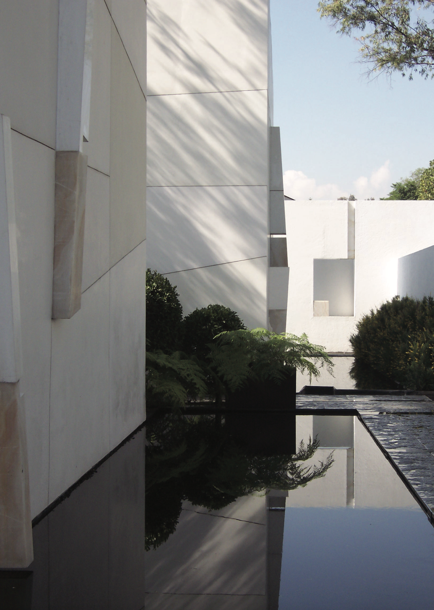 Edificio moderno de paredes blancas, árboles y cielo azul en el fondo.