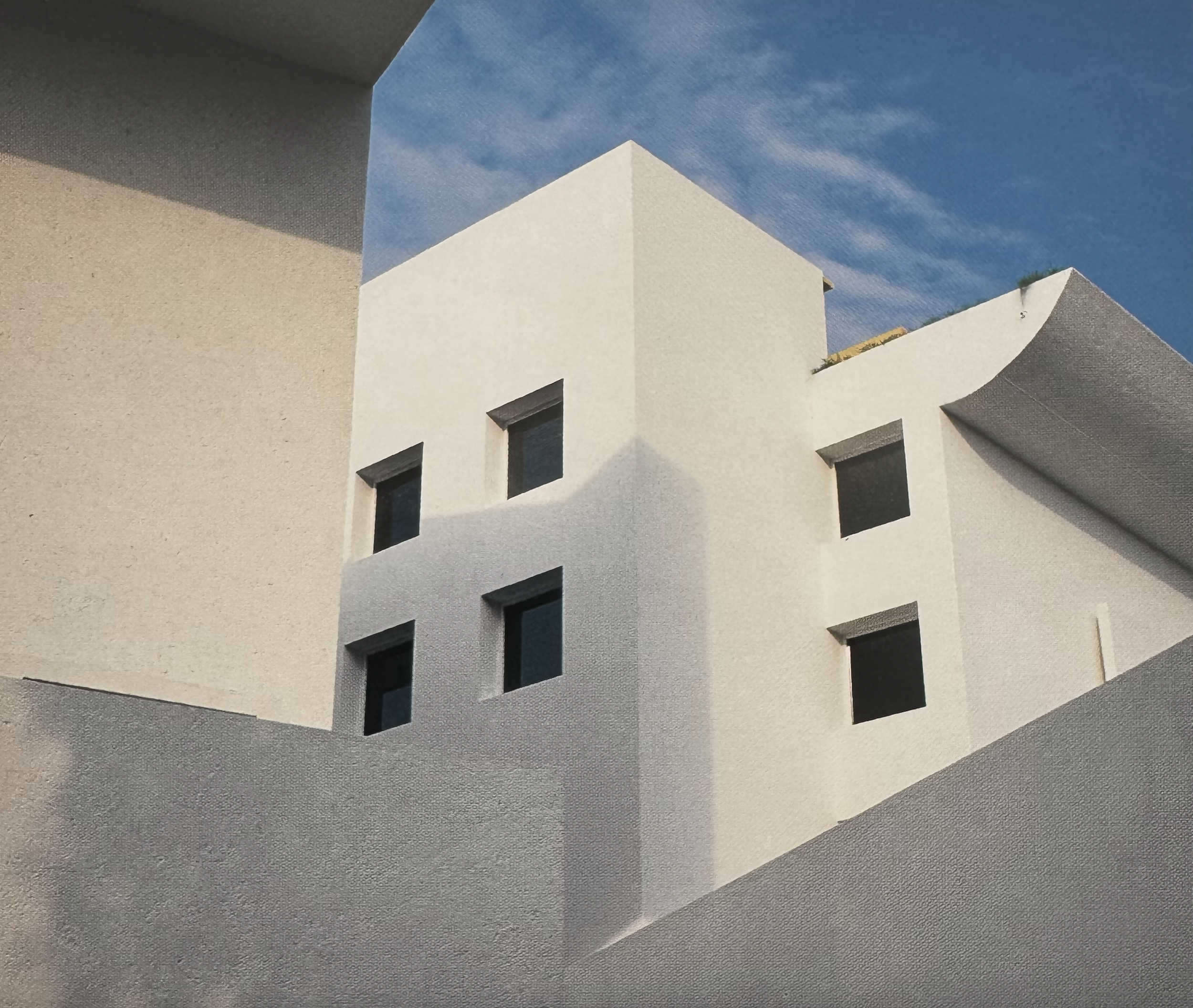 Edificio moderno de color blanco con ventanas cuadradas, bajo un cielo azul con algunas nubes parriba.