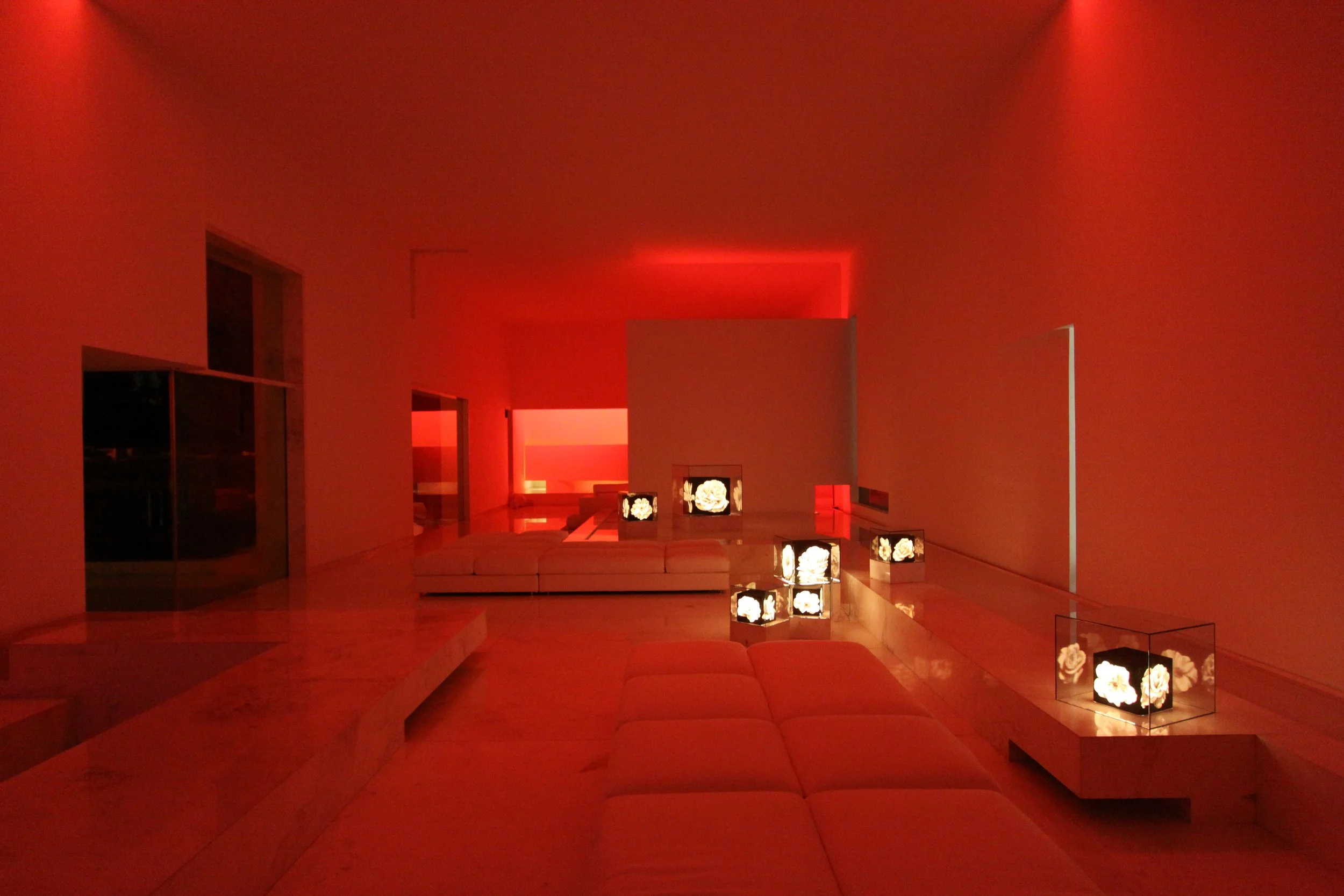 Sala moderna con luz roja, sillones blancos y lámparas decorativas con flores blancas