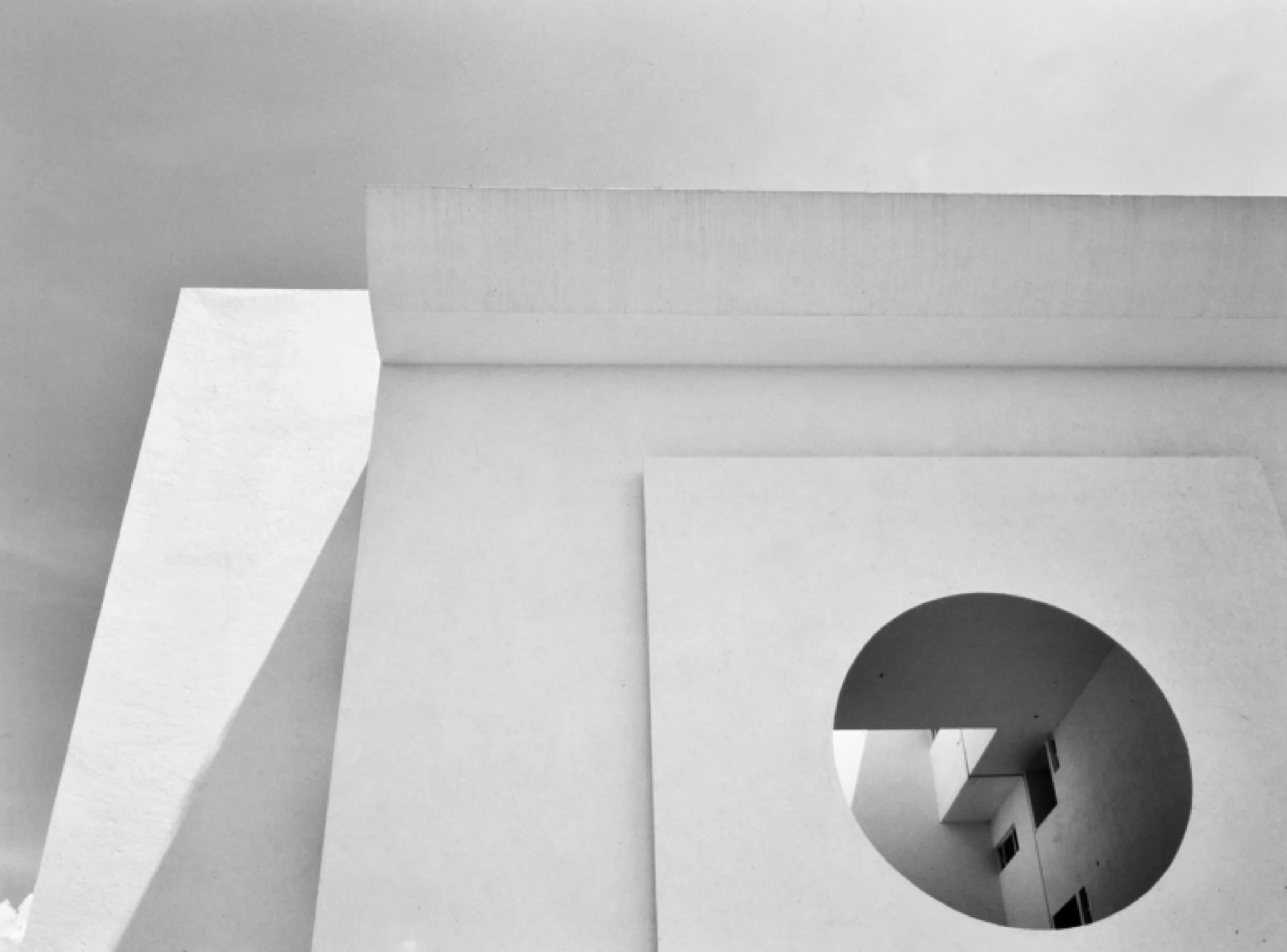 Imagen en escala de grises de varias páginas de papel apiladas, con algunas sombras y un círculo negro en la esquina inferior derecha.