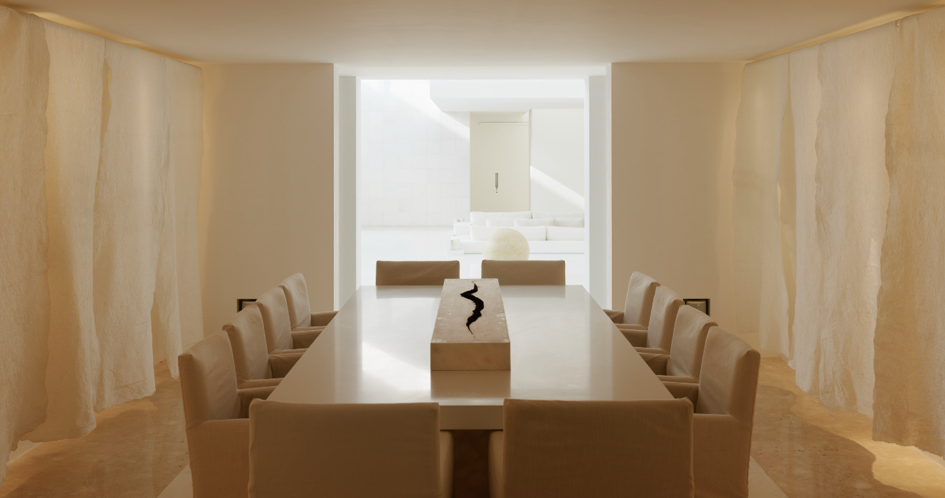 Sala de reuniones con mesa larga, sillas blancas, paredes decoradas con telas blancas, y un fondo luminoso de ambiente minimalista. Eucaliptos 65, Architecture & Design by Rafael Aragonés Caballero & Miguel Ángel Aragonés | Taller Aragonés. Photo by 