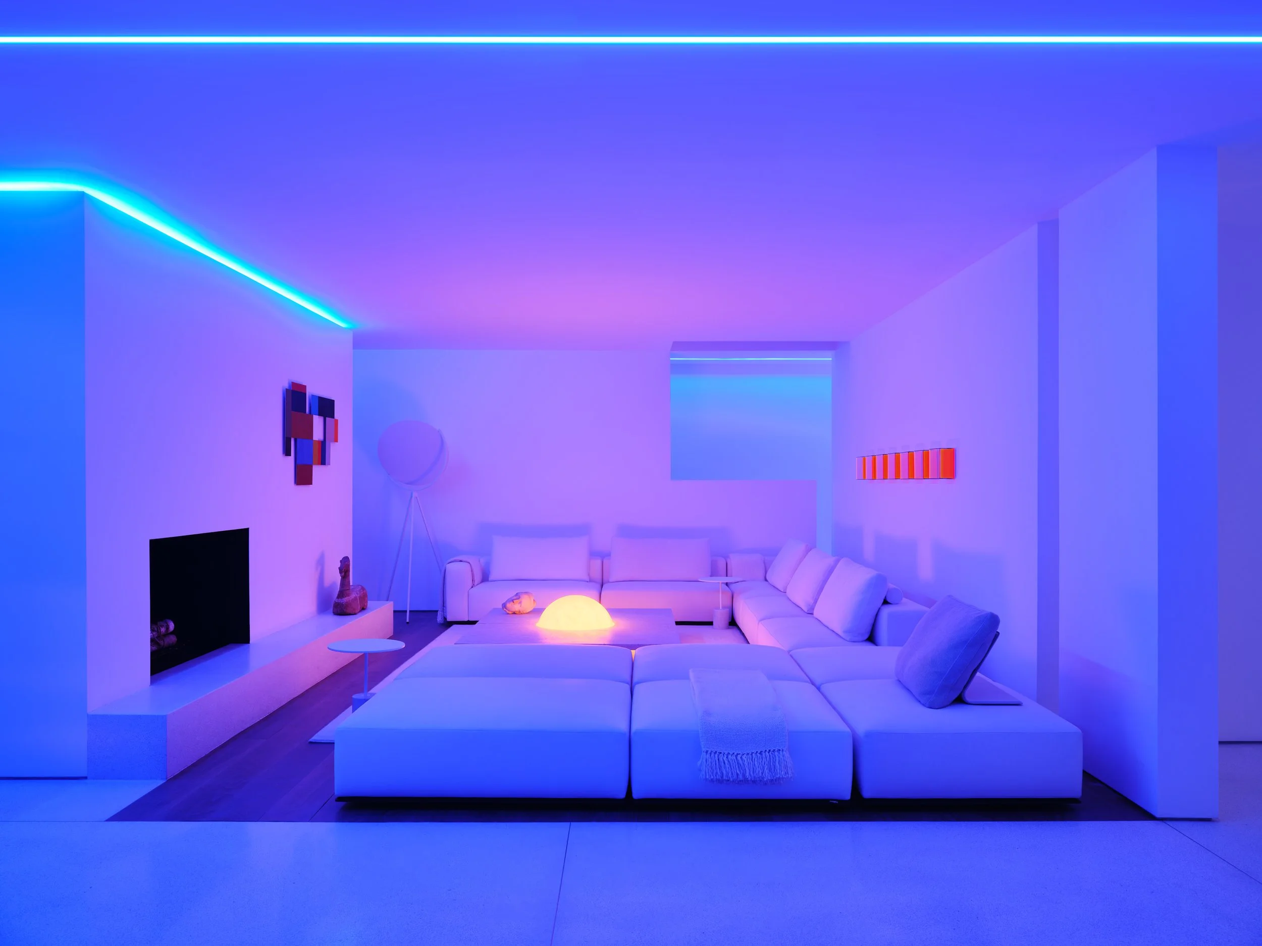 Sala de estar moderna con luz azul, sillones blancos, mesa de centro, arte abstracto en la pared y lámpara de pie.