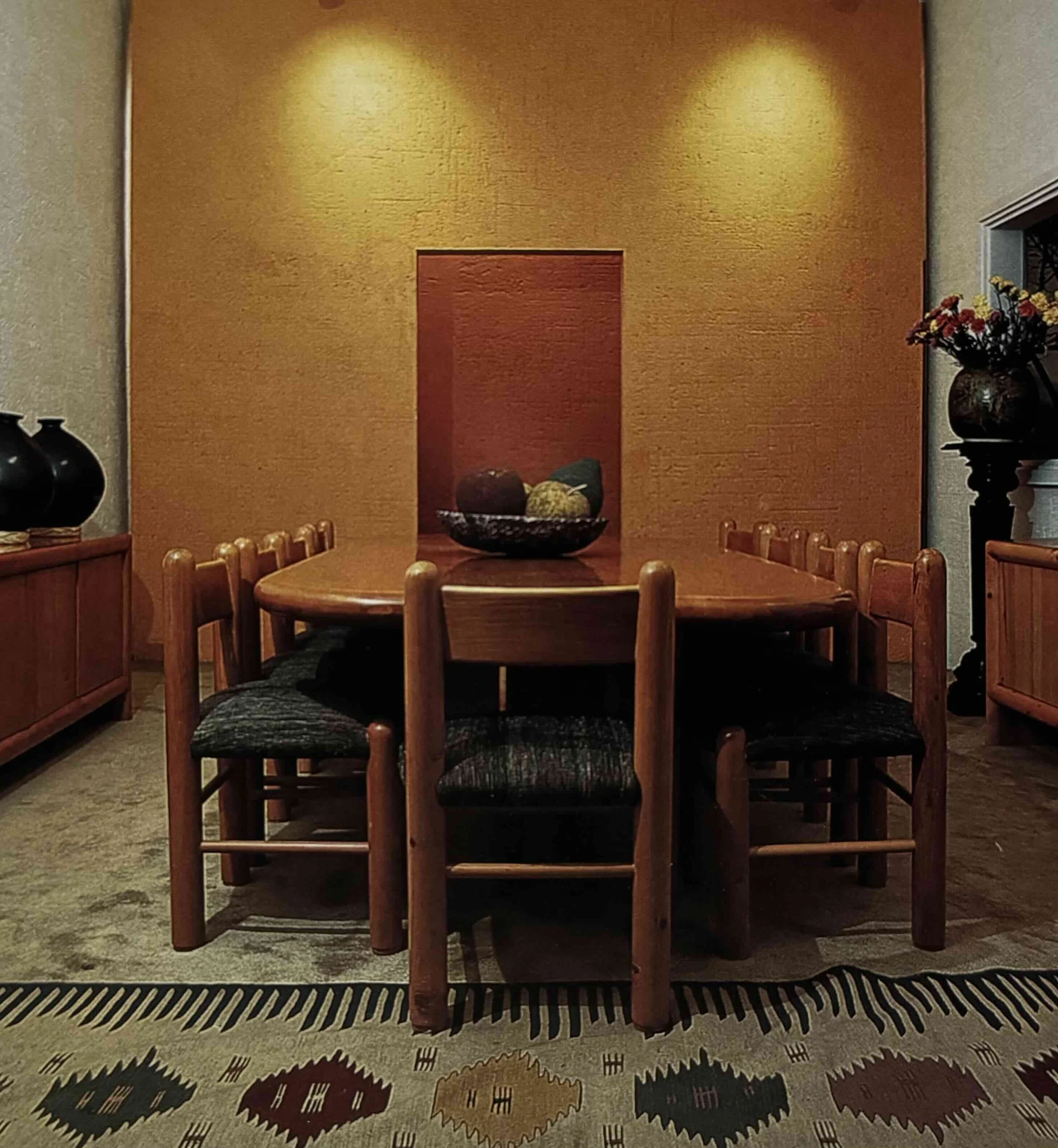 Comedor con mesa de madera y sillas, decoración con un florero y un cuadro en la pared.