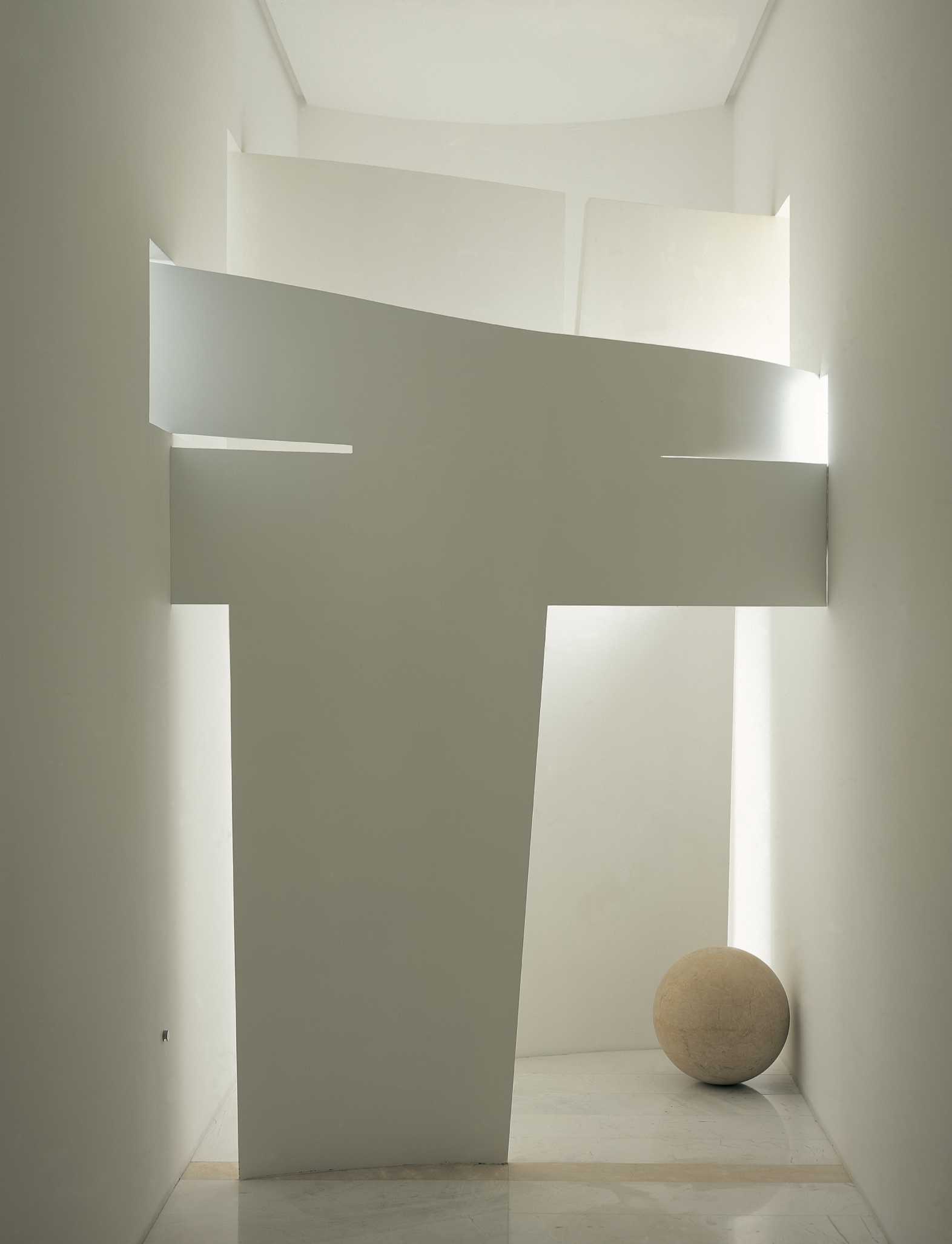 Vista de un pasillo minimalista con paredes blancas, con una escultura de un globo terráqueo en el extremo derecho. Eucaliptos 65 (2004). Eucaliptos 65 (2004). Designed by  Miguel Ángel Aragonés. A study in geometric volumes and natural light. Mexica