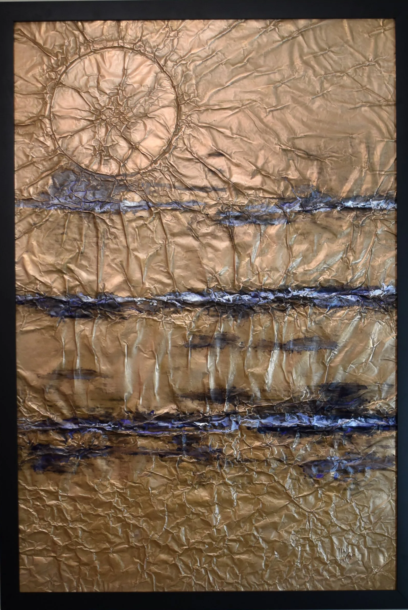 Textured gold-toned abstract artwork with horizontal blue bands and a large circular form in the upper left. Shown close up in a black frame.