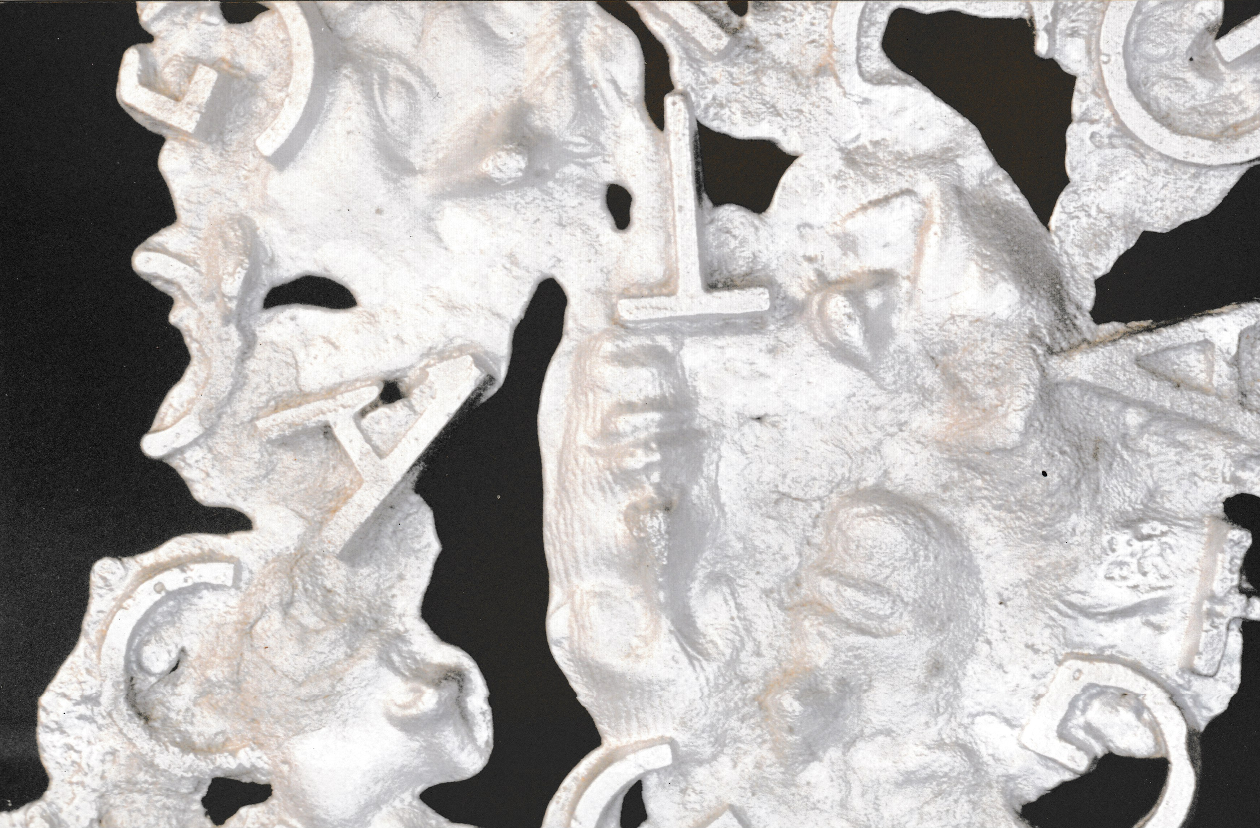 Detailed section of a relief sculpture combining human profiles, symbols, and raised lettering.