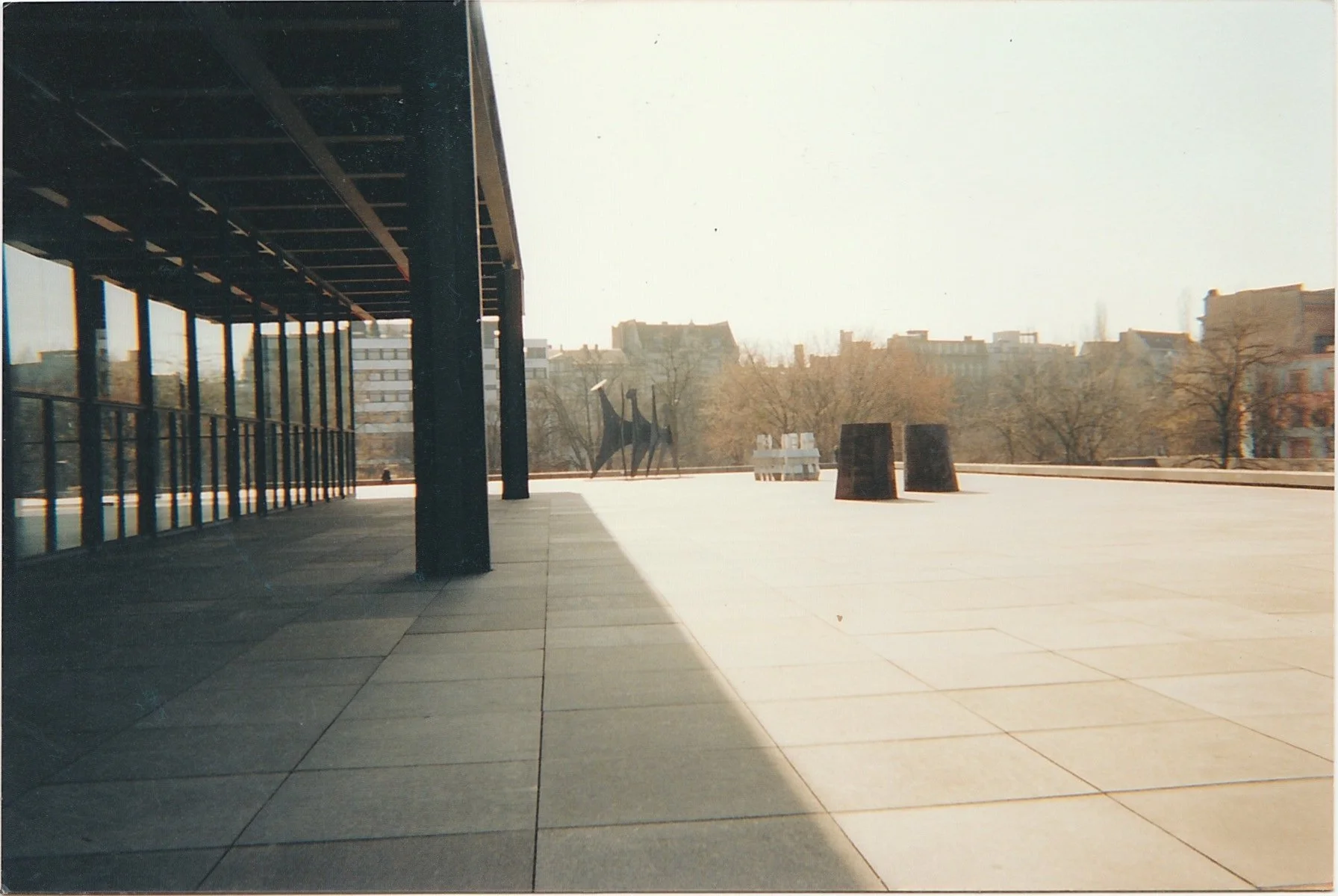 Large open plaza with long shadows cast across pale stone paving.