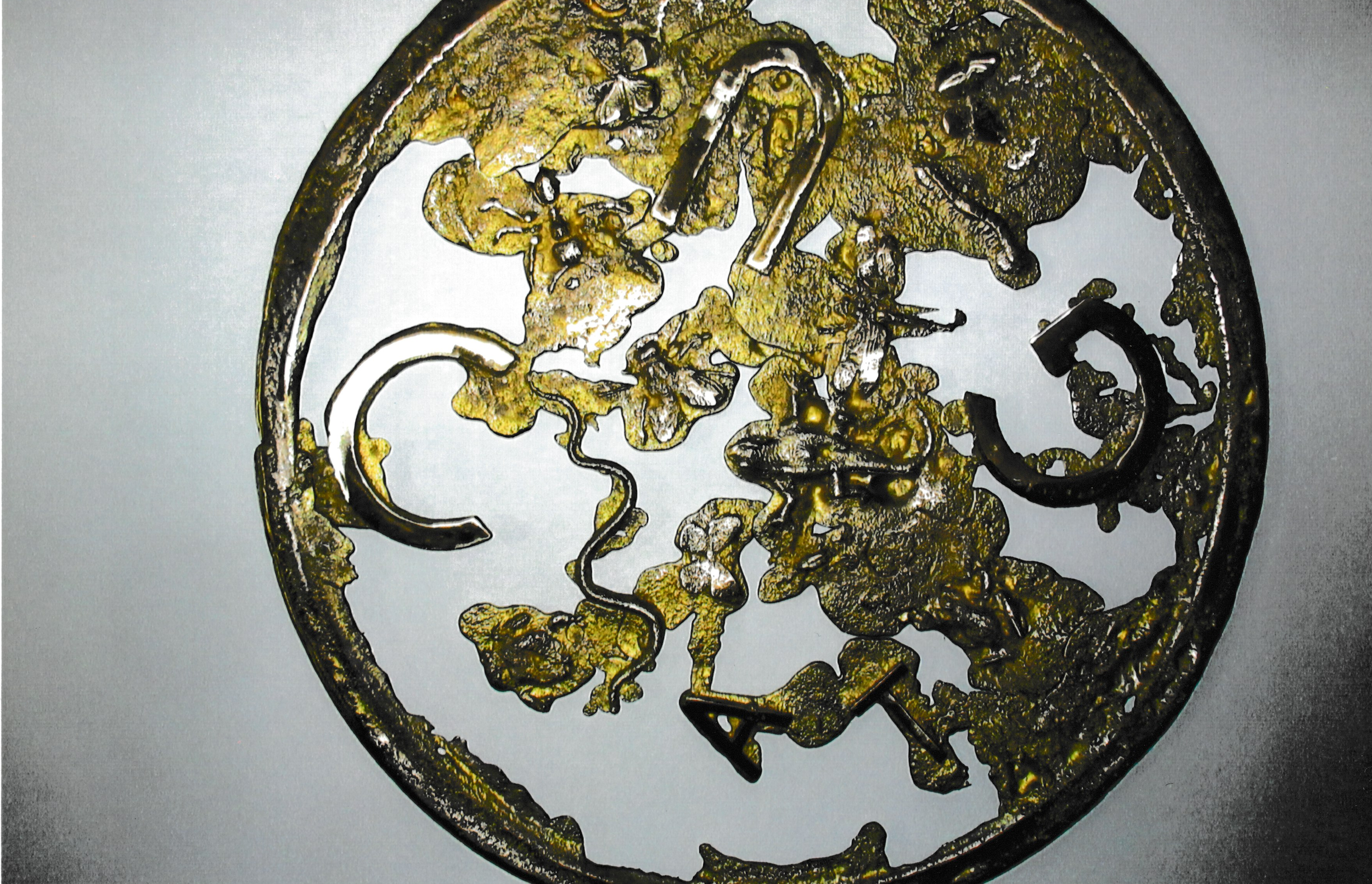 Circular bronze-toned sculpture containing intertwined organic and abstract forms within an open ring.