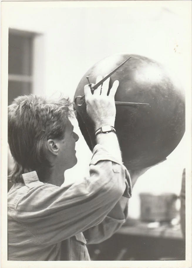 Whitney Wolf II featured in a black-and-white photo where he is looking into one of his giant spheres. Circa 1980s