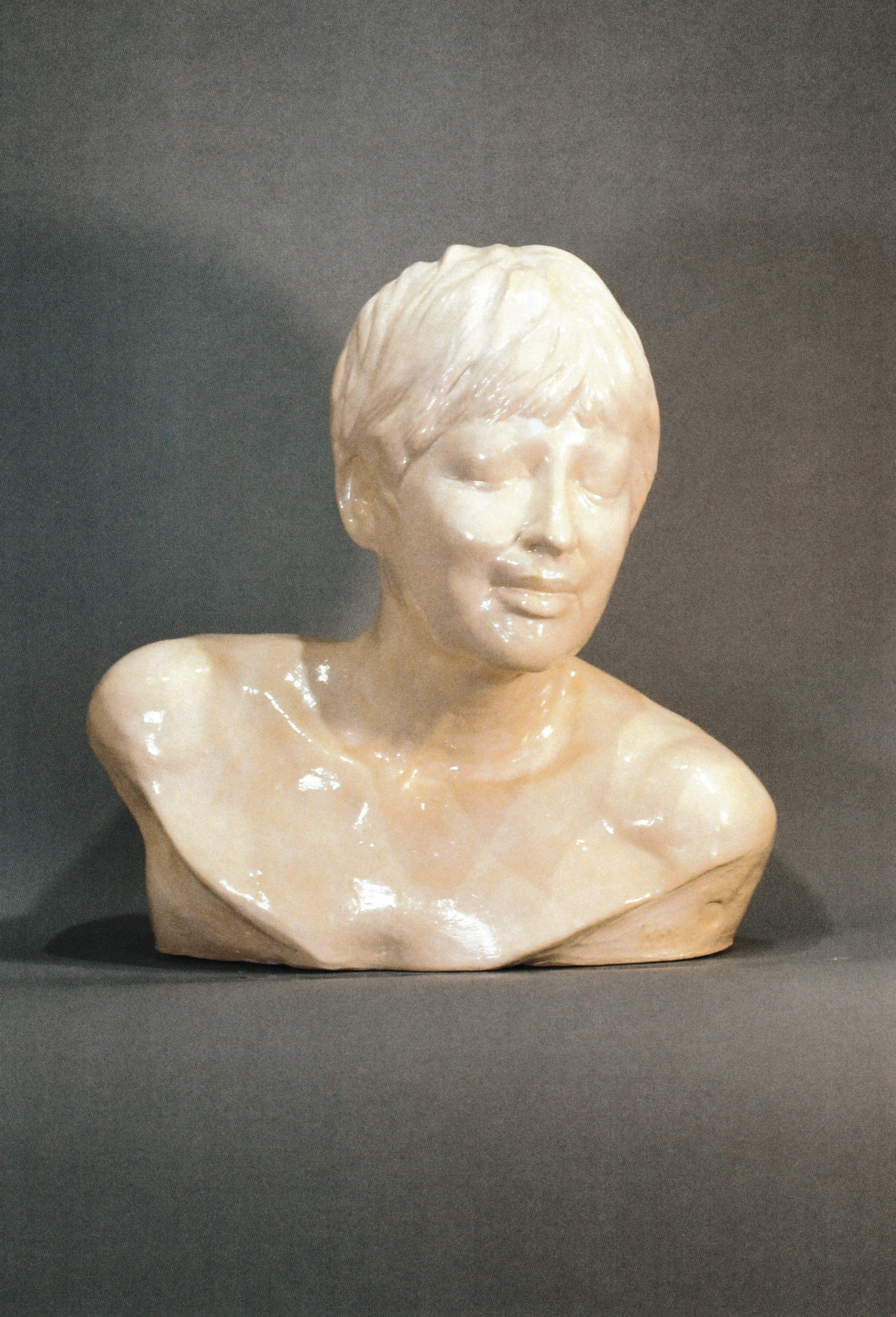 Ceramic life cast bust of a smiling young person with short textured hair and softly modeled features.