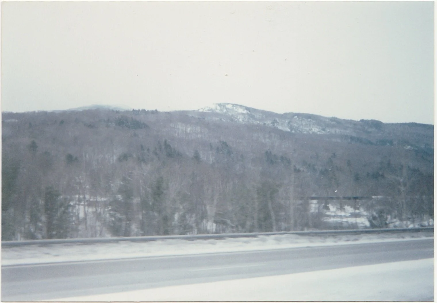 Snow-covered mountain landscape viewed from a roadside.