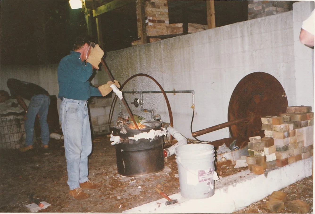 Whitney Wolf II wearing a mask and protective gear while working with hot liquid metal. EST 1980s