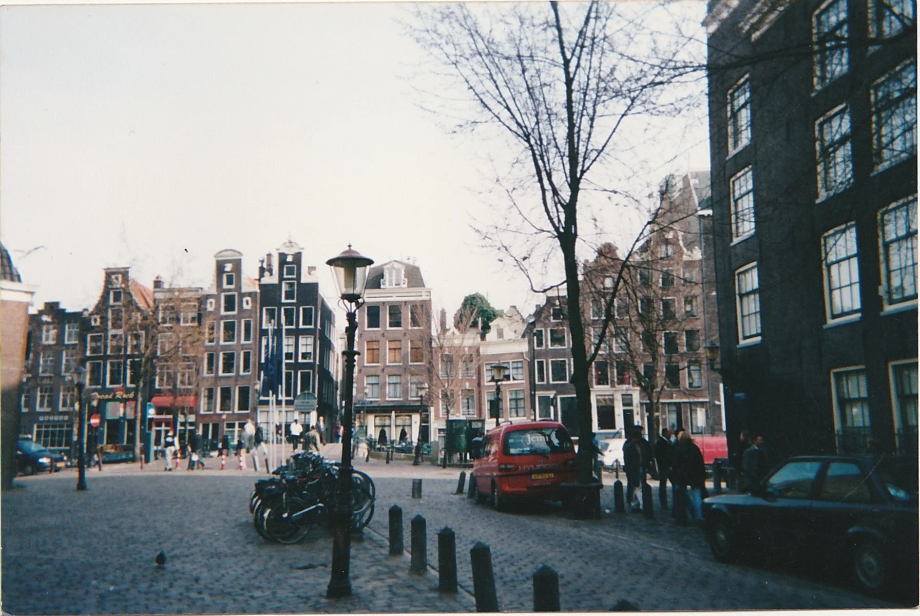 Historic Amsterdam square lined with narrow canal houses and parked bicycles.