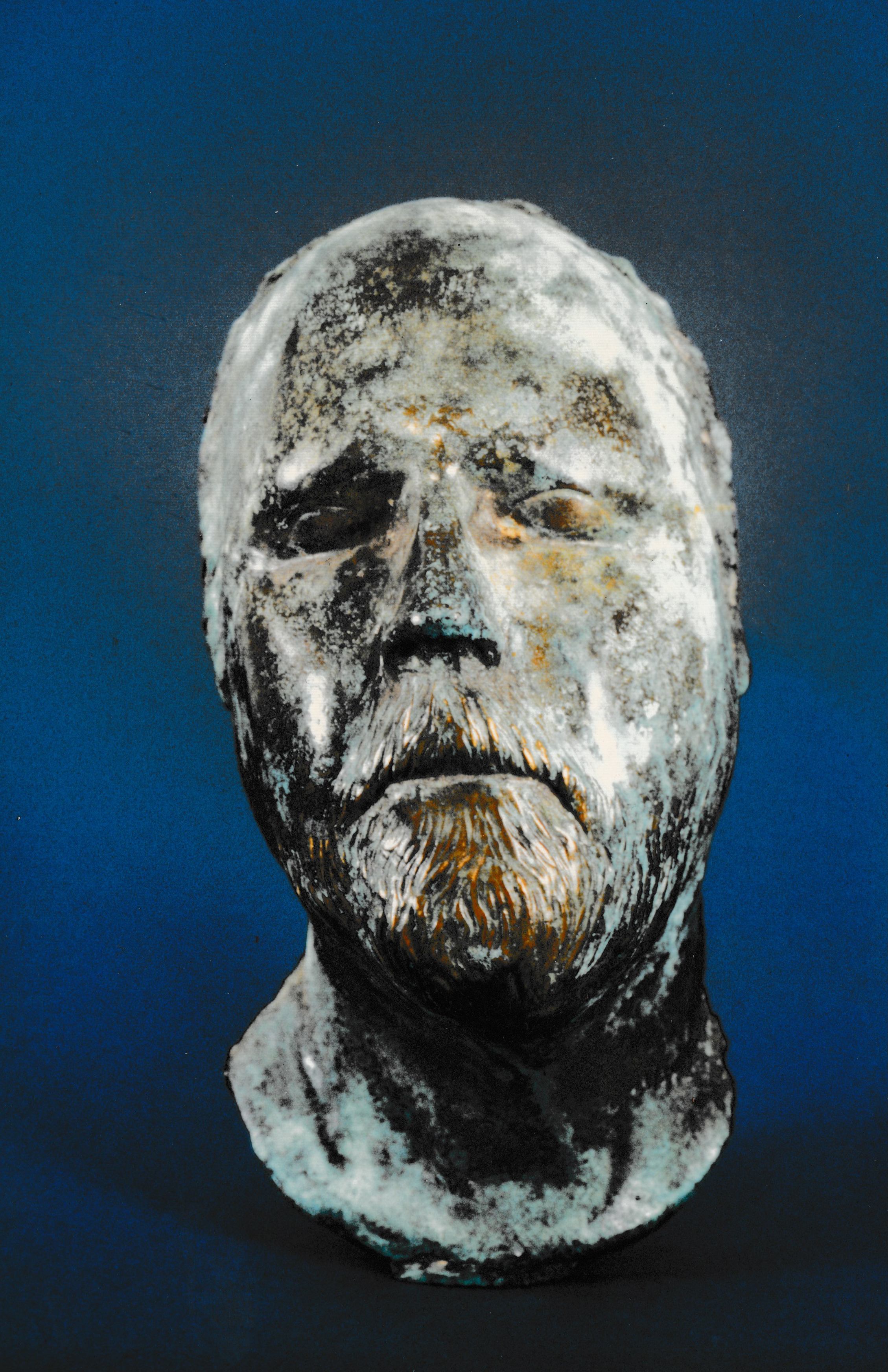White-patinated portrait bust of a bearded man with closed eyes and weathered, stone-like surface textures.