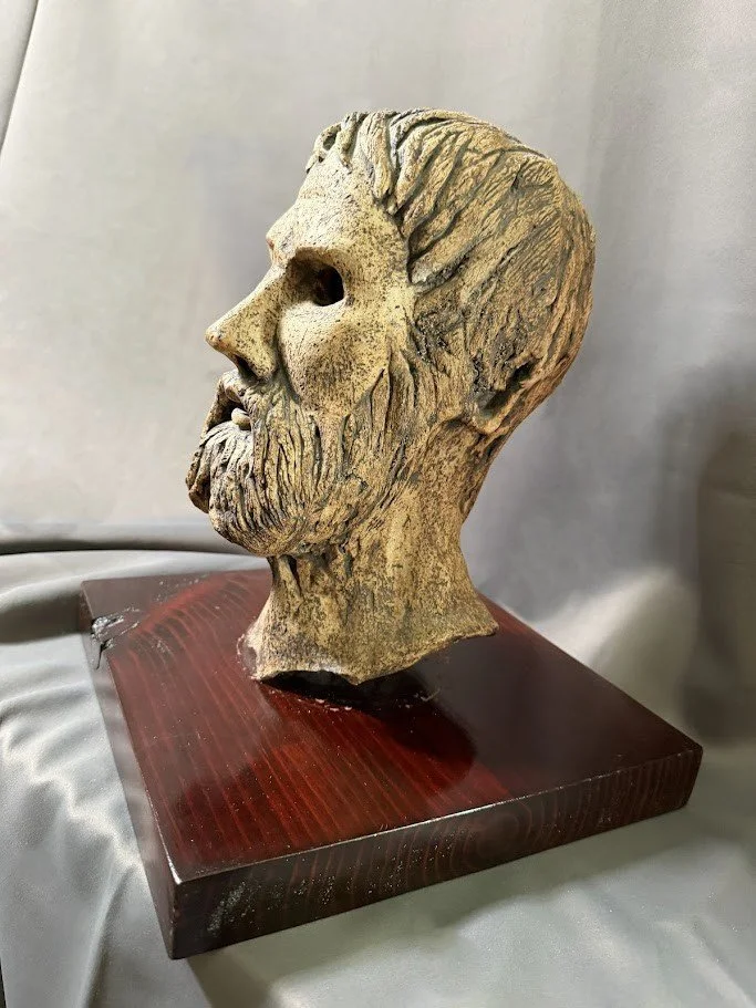 Upward angled profile of the mask emphasizing the elongated neck, pointed beard, and hollow eye openings.