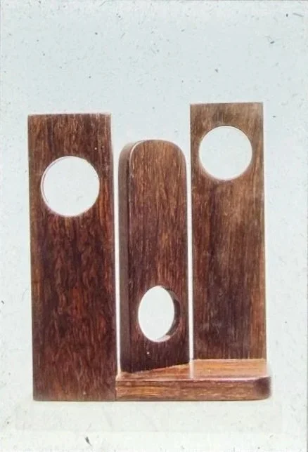 Three vertical wooden panels with circular cutouts arranged in a geometric composition.