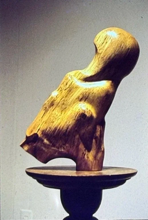 Small carved wood sculpture suggesting a simplified human torso and head.