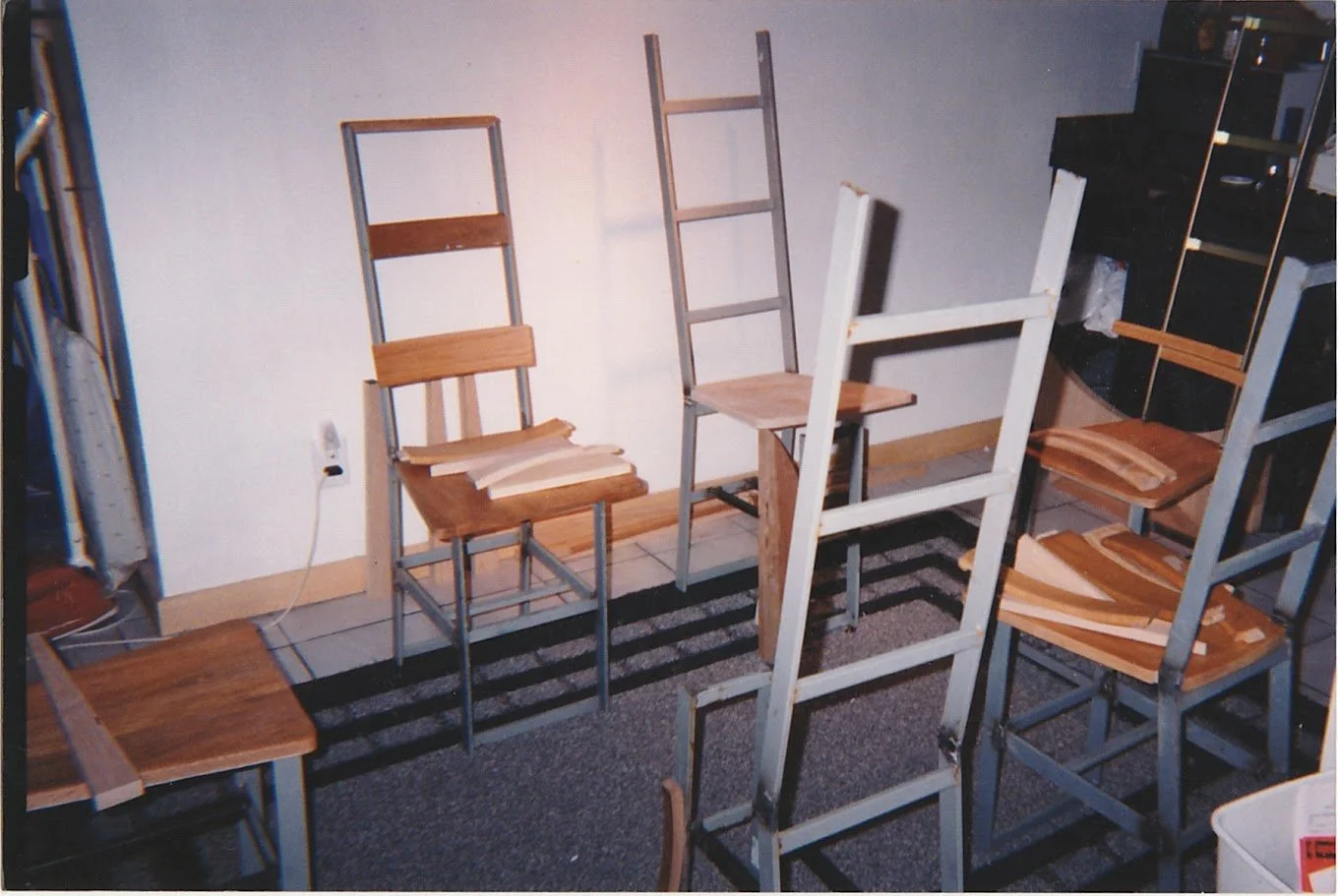 Multiple ladder-back chairs grouped together in a workshop or studio setting.