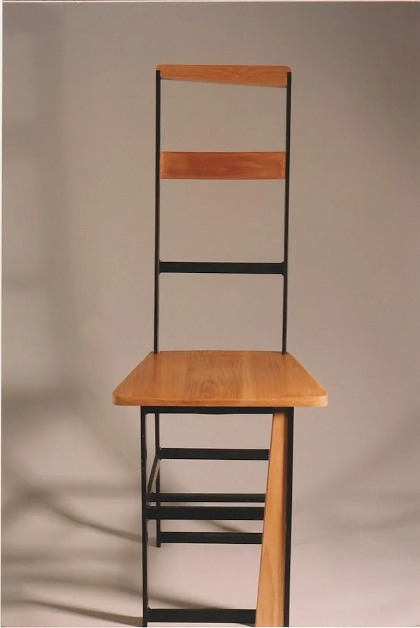 Front view of a tall geometric chair with elongated backrest and square seat.