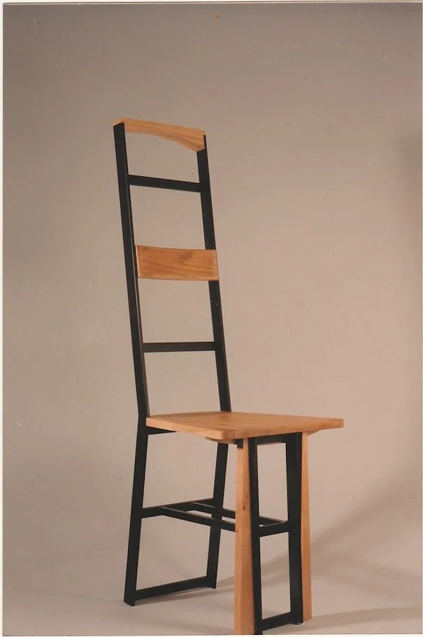 Side-angle view of the geometric chair emphasizing the vertical black metal frame.