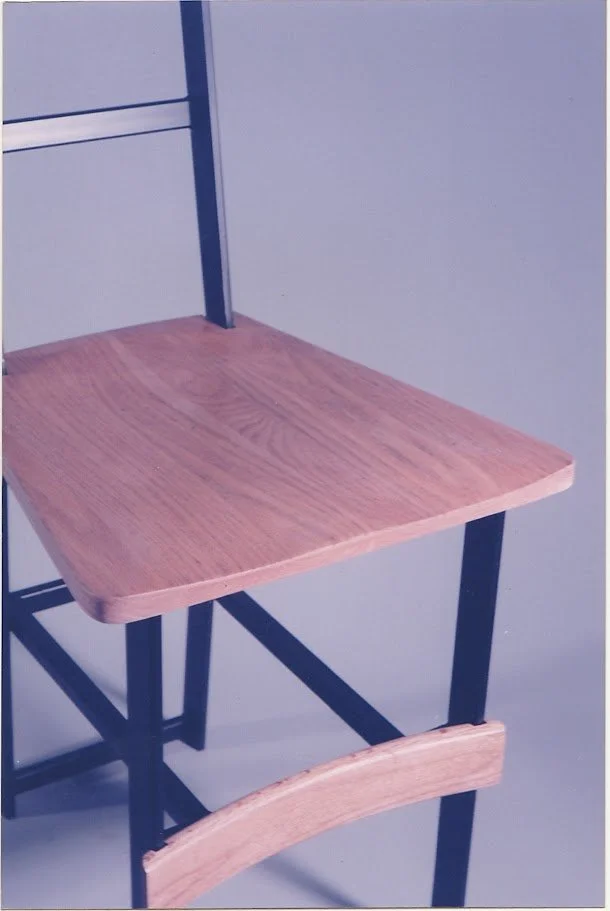 Close-up view of the chair seat showing wood grain and black metal supports.