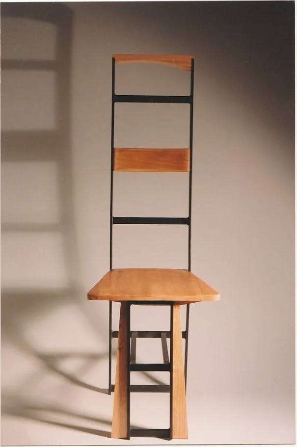 Front-facing view of a geometric chair with square wooden seat and towering ladder-like back.