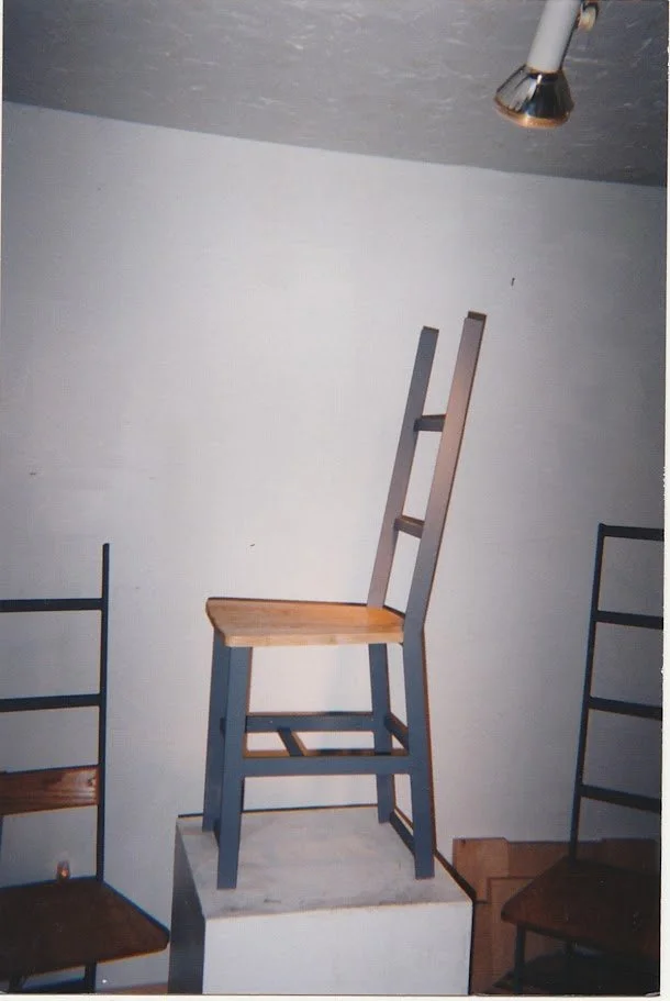 Sculptural ladder-back chair with black metal frame and warm wood accents displayed in a studio.