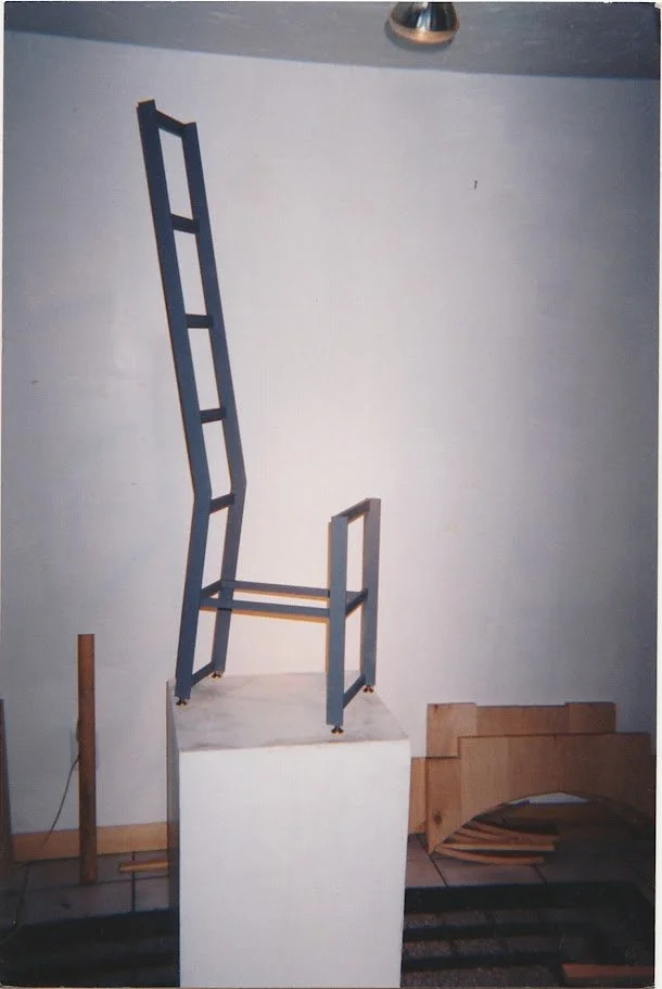 Tall ladder-back chair displayed on a pedestal with an elongated open backrest.