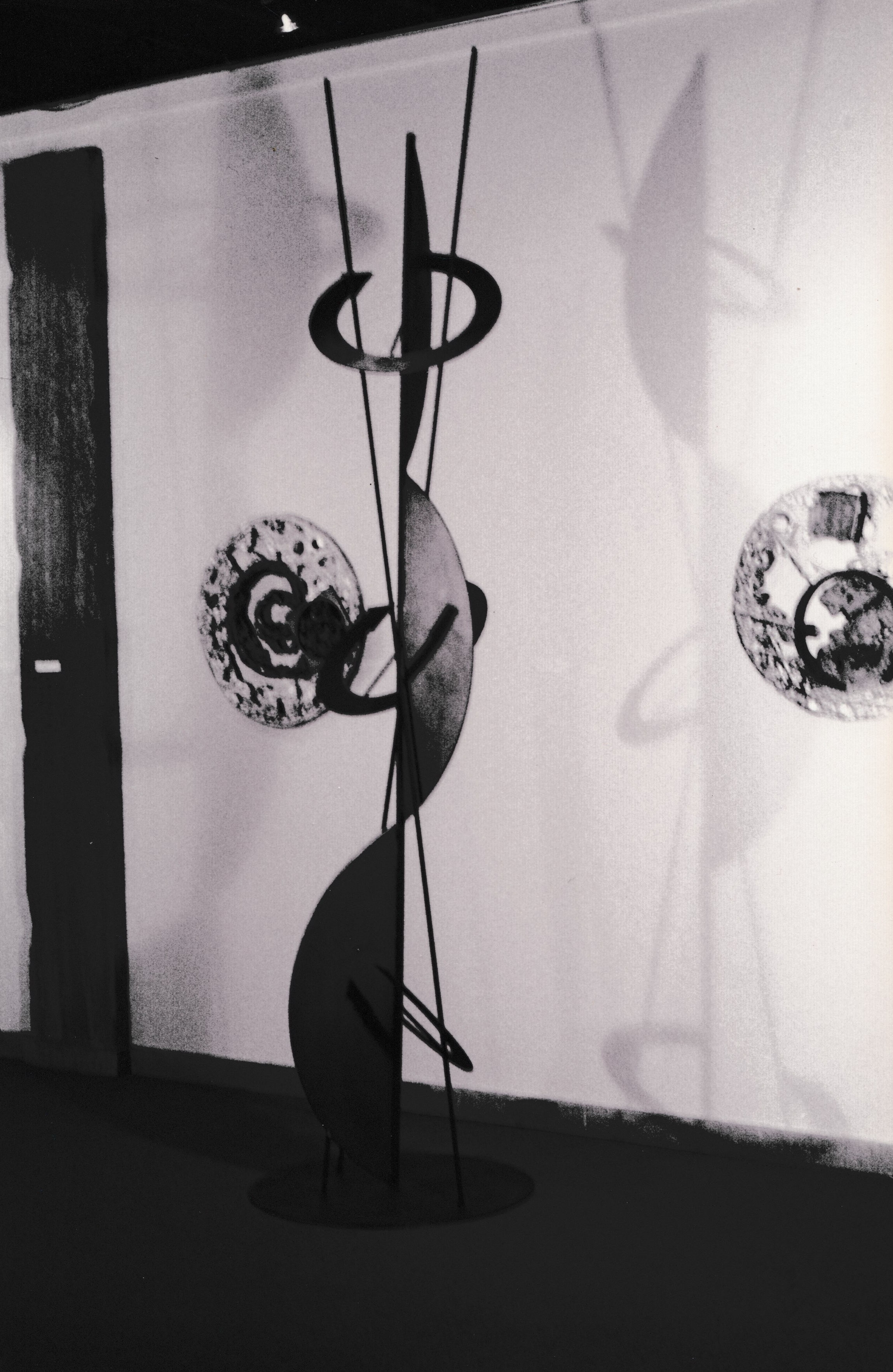Tall sculptural installation composed of circular forms suspended on slender vertical rods.