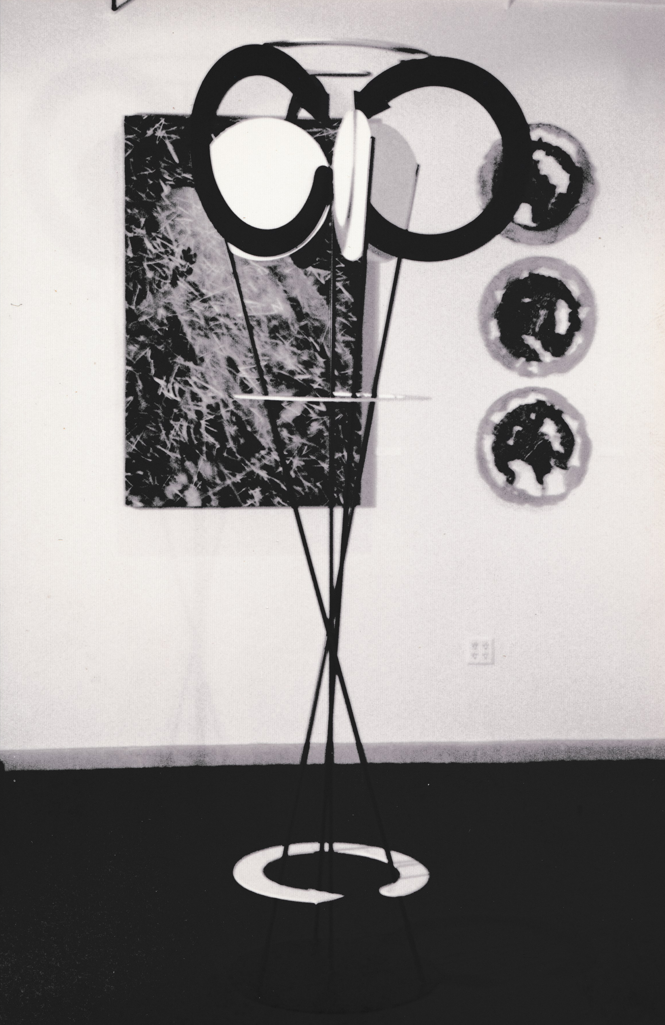 Geometric wall installation combining circular forms, vertical rods, and abstract black-and-white panels.