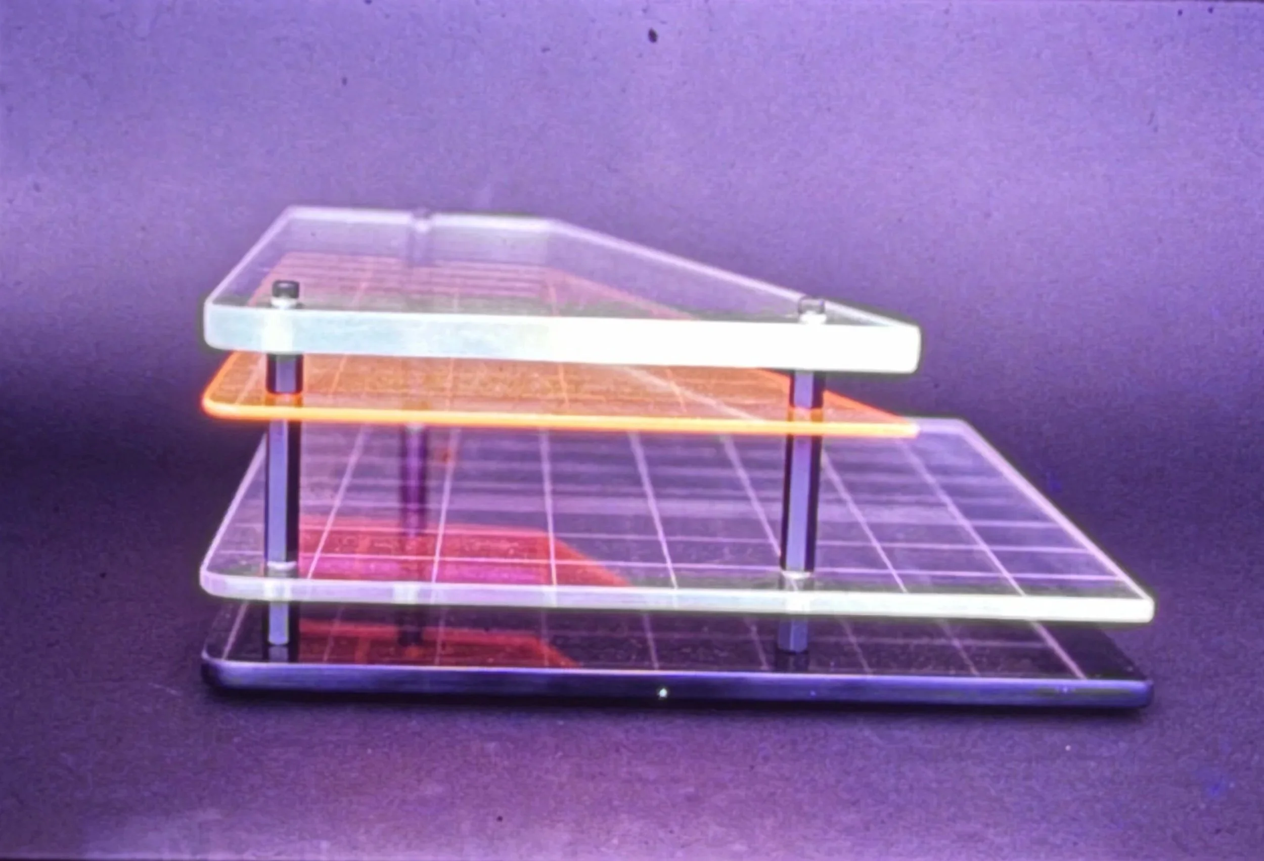 Acrylic sculpture featuring stacked transparent planes and grid lines arranged in a stepped geometric structure.