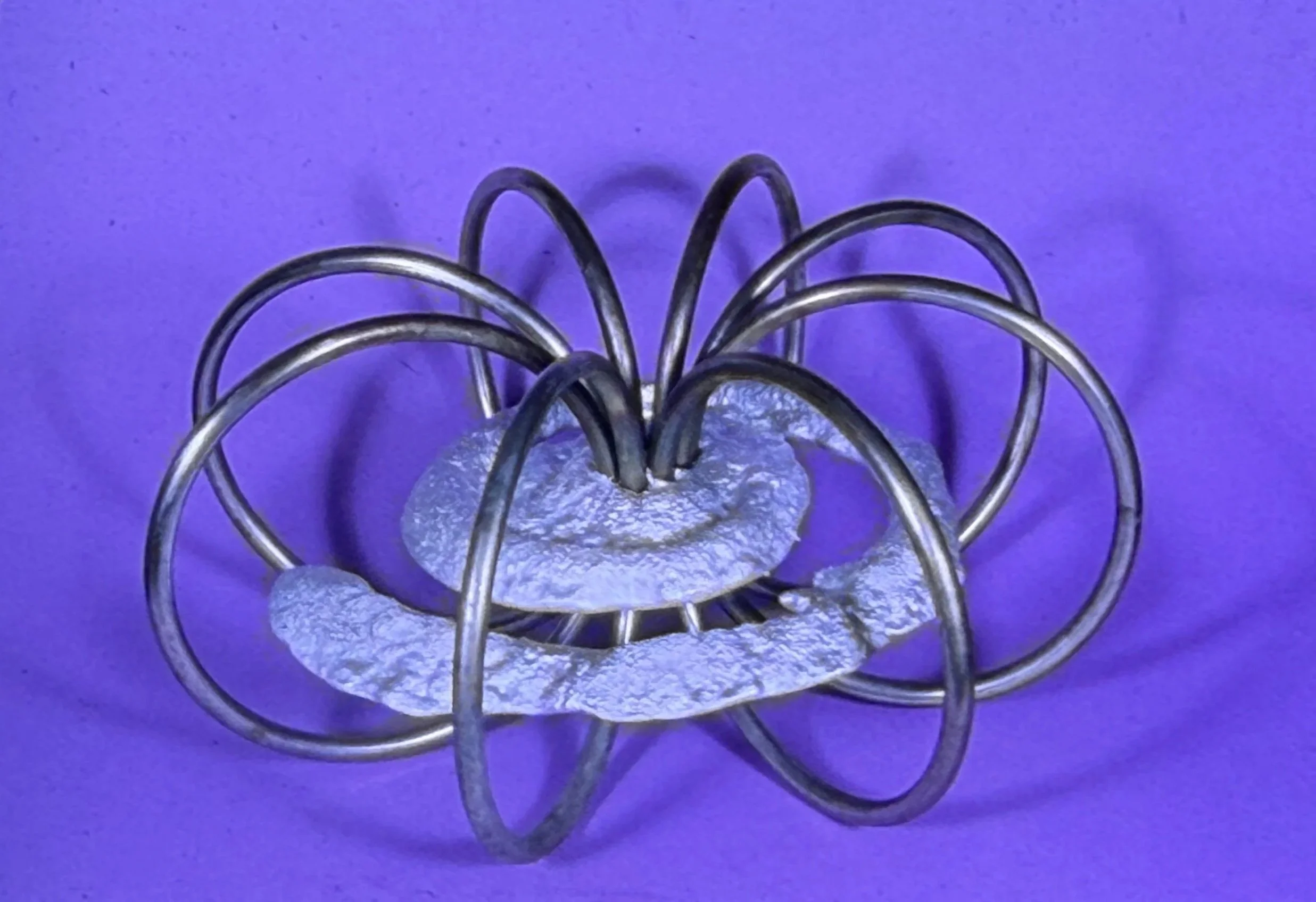 Large ring-based sculpture formed from overlapping circular metal arcs around a central core.
