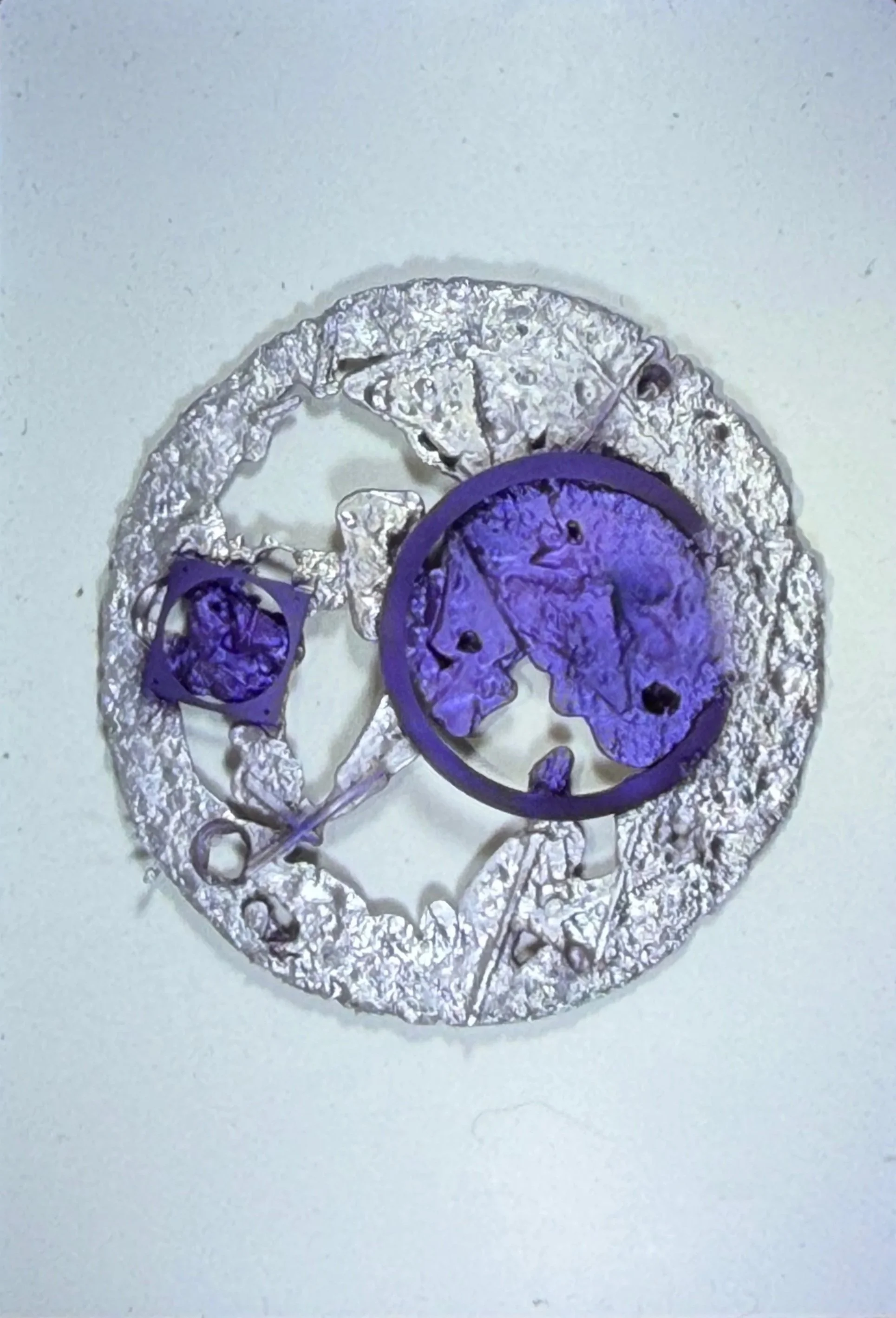Circular relief sculpture combining purple geometric forms with intricate white textures.
