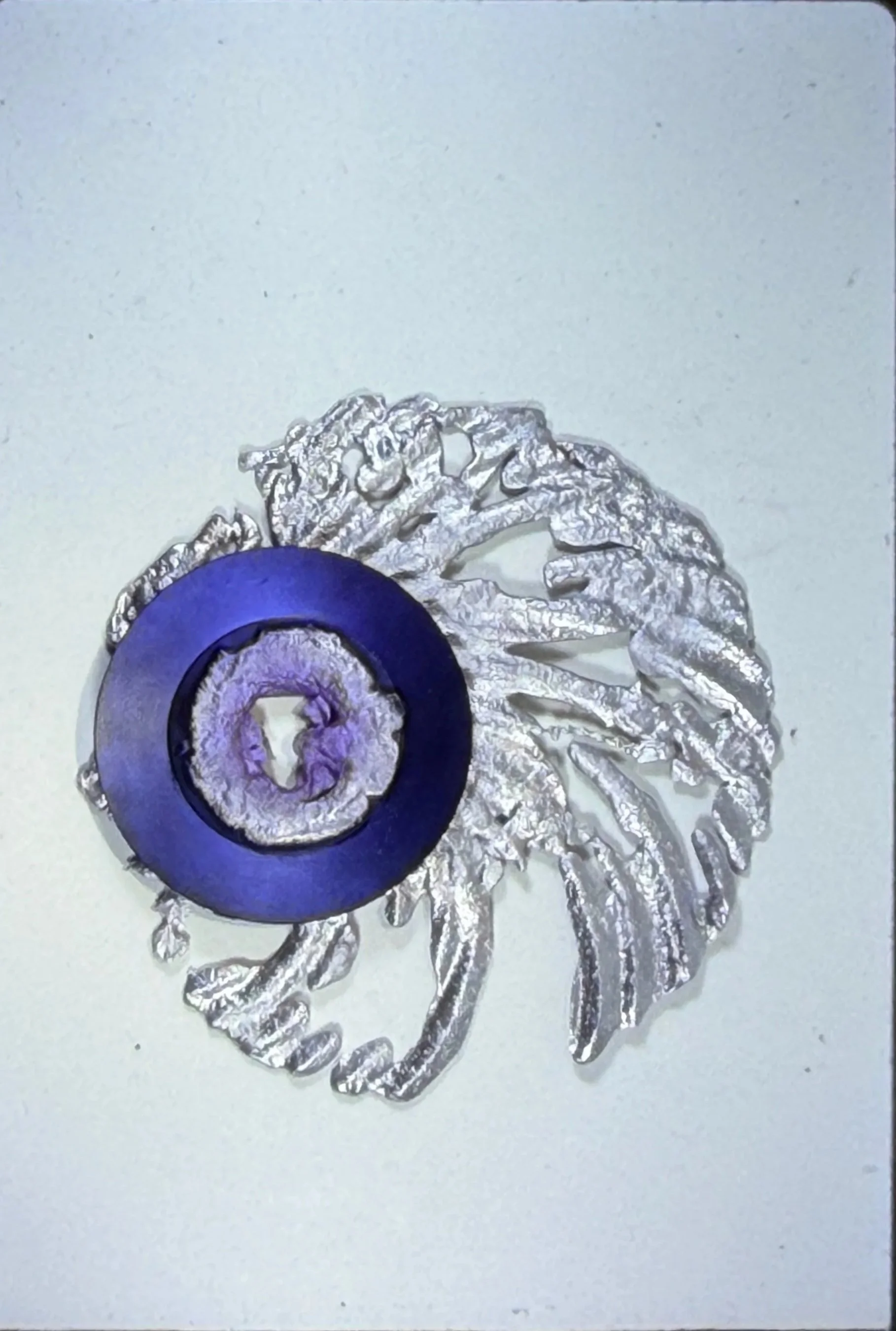Spiral-shaped relief sculpture featuring a central purple circle surrounded by radiating white forms.